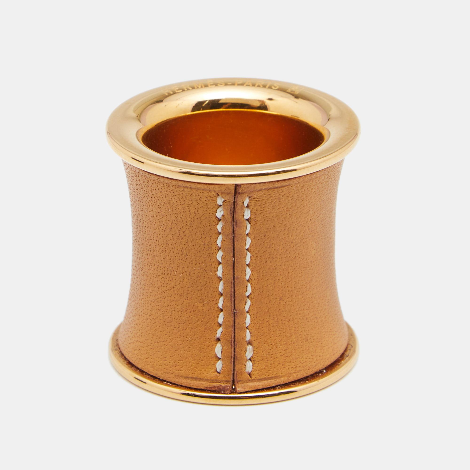 Use this elegant and valuable piece by Hermès to secure your favorite scarf ties in style! The ring is crafted from gold-plated metal and is accentuated with a brown leather covering. Replace the knot with this chic ring for a simpler and more