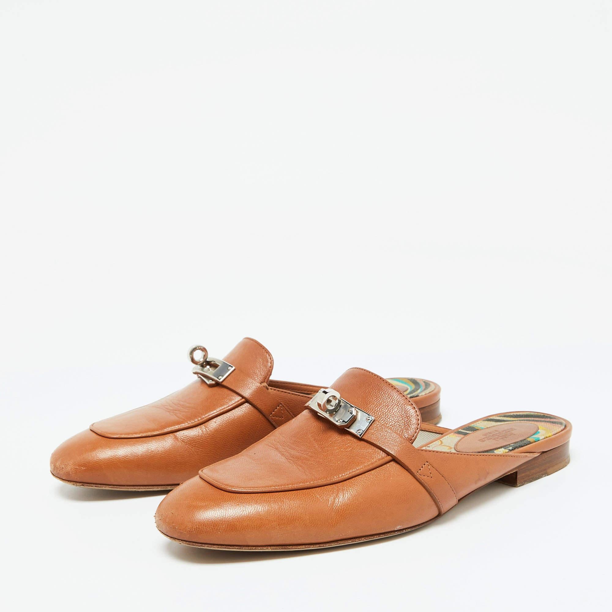 Designed in a loafer style  these mules are from the house of Hermes. They are beautifully crafted in brown leather with the signature twist lock in silver plated metal on the vamps. Slip these flat mules on for a comfortable urbane style.