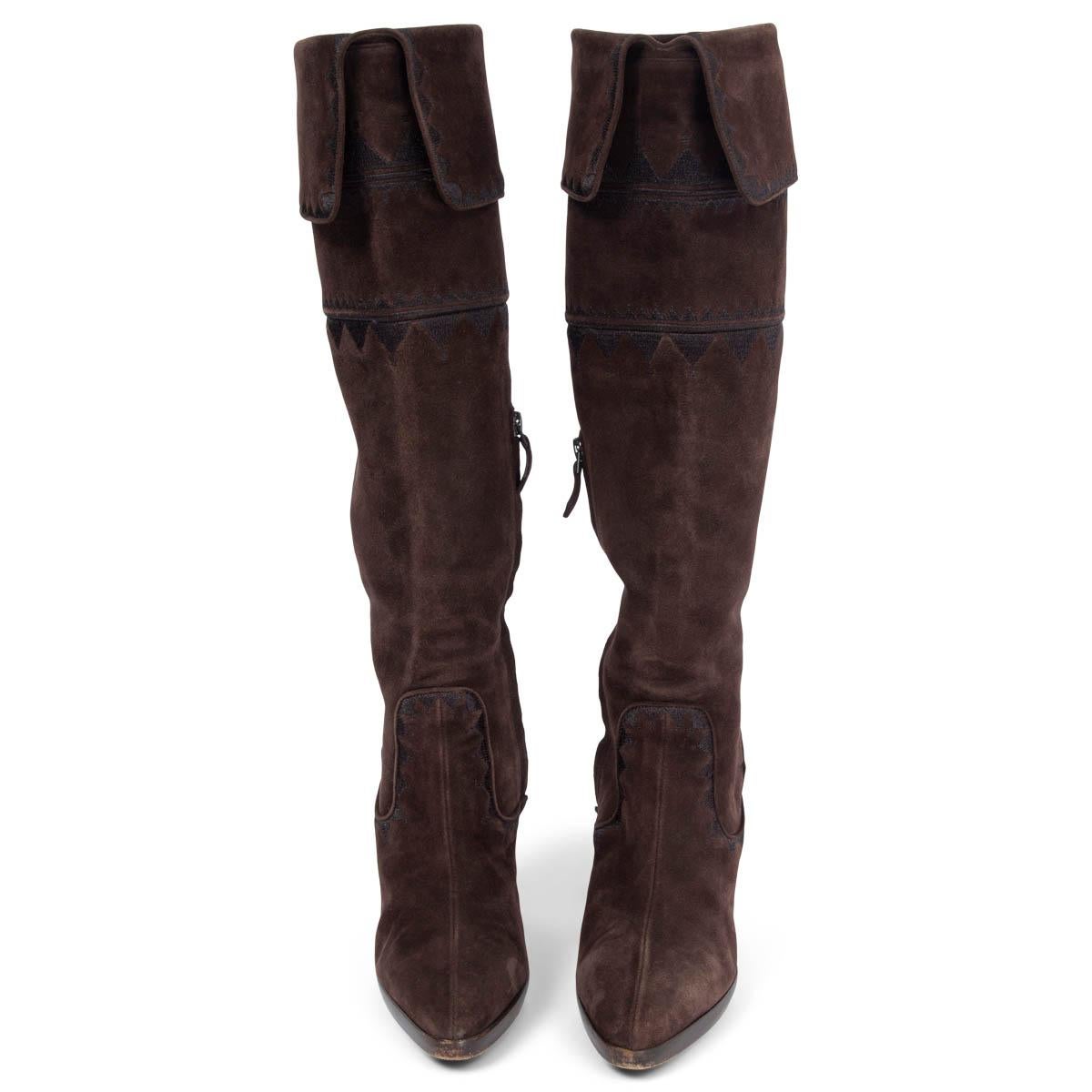 100% authentic Hermès knee-high boots in dark brown featuring a stacked heel, black complementing zigzag embroidery and a fold-over top. Open with an inner-zipper. Have been worn with overall light signs of use and wear to the tips. Generally in