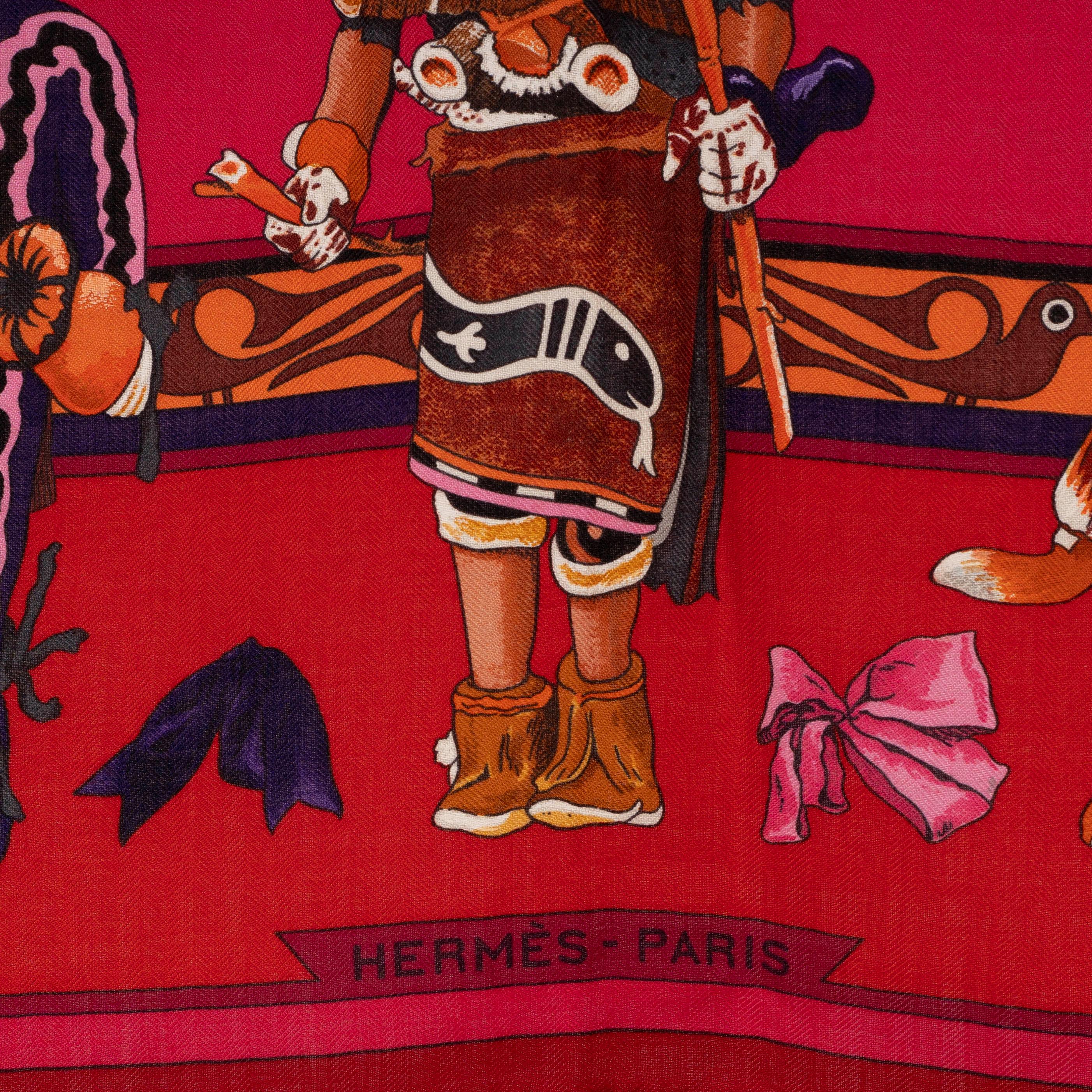 This 100% authentic Hermès Kachinas 140 shawl, designed by Kermit Oliver, is crafted from a luxurious blend of burgundy and raspberry cashmere (65%) and silk (35%). It features an Indian doll-inspired print in vibrant shades of cream, taupe, orange,