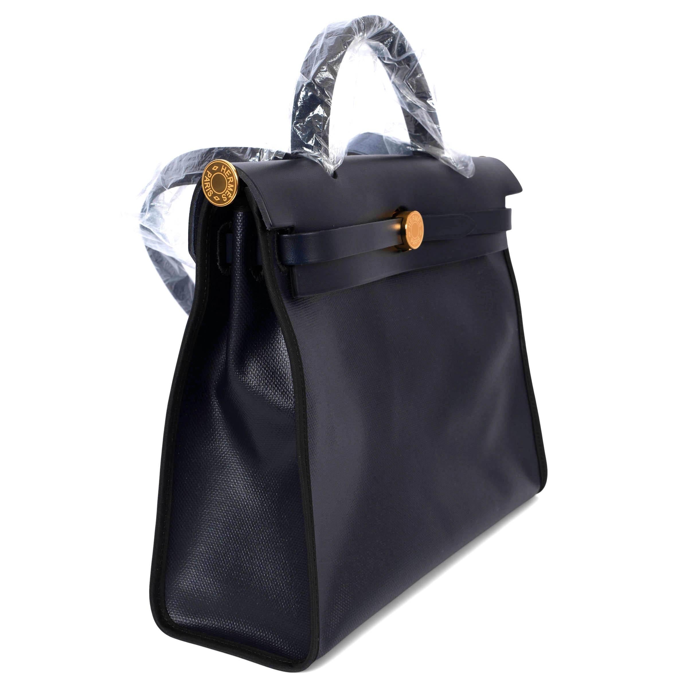 100% authentic Hermès Herbag Zip 31 in Caban blue coated Toile H Berline and Indigo Vache Hunter leather with gold-tone hardware. The design features an exterior zip pocket on the back, has tonal stitching, front flap, clochette with lock and two