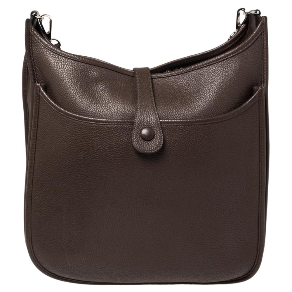 Die Evelyne ist eine weitere investitionswürdige Tasche von Hermès. Diese hier in der Größe GM ist aus Togo-Leder gefertigt und mit den charakteristischen Elementen der Lederlasche, der sattelähnlichen Form und dem perforierten H auf der Vorderseite