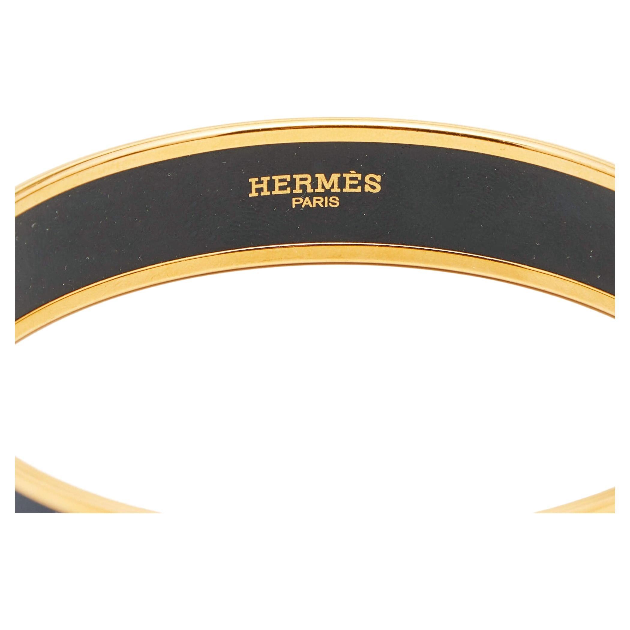 Exuding glamour and classic style, this stunning bangle bracelet from the House of Hermes is something you'll love having around your wrist. It is a gold-plated metal creation that is enhanced with black enamel. Featuring iconic brand details, this