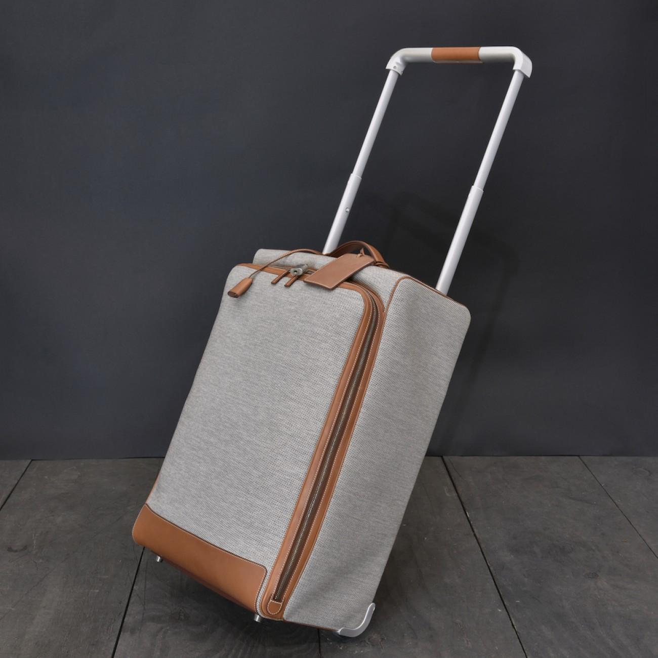 A modern carry-on sized suitcase by Hermès in barely used condition. Constructed from water and stain resistant 'H-tech' ecru canvas and fawn berenia calfskin leather with brushed silver and palladium hardware, plus a palladium plated aluminium pull