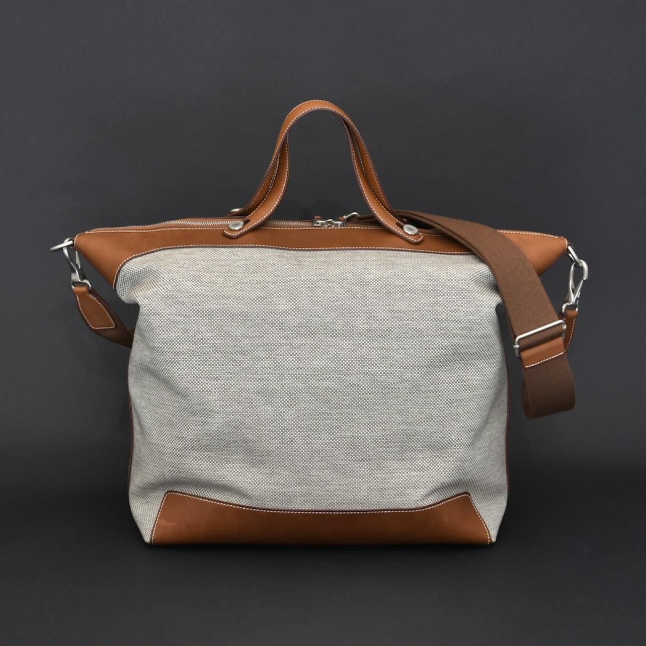 A modern travel bag by Hermès in barely used condition. Constructed from water & stain resistant 'H-tech' ecru canvas and fawn berenia calfskin leather with brushed silver and palladium hardware. The bag has a detachable shoulder strap, flat top