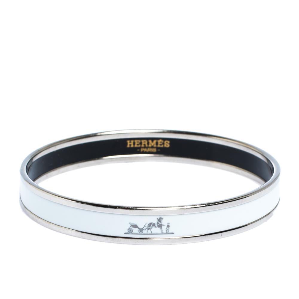 Beautify your wrist with this stunner of a bracelet from Hermes. The piece has been crafted from palladium-plated metal and has white enamel coating on the exterior. This bracelet is complete with the iconic label at the front and on the inside of
