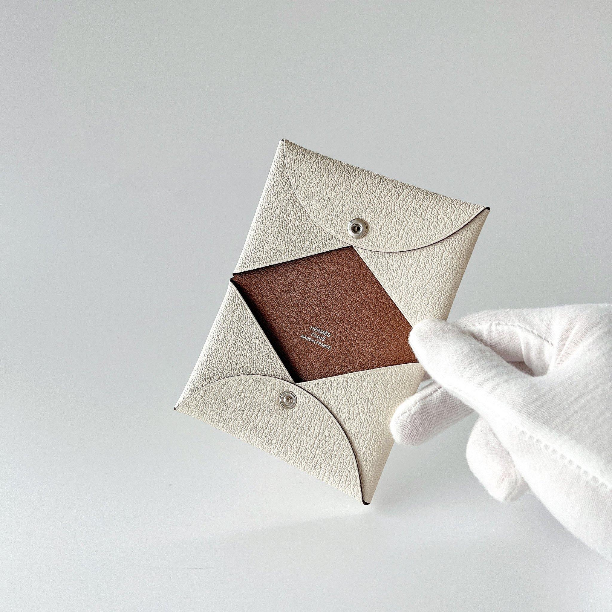 This Hermès Calvi Duo Card Holder in Nata is made from luxurious Mysore goatskin leather, it features a snap closure, 1 credit card slot, and 1 pocket. This beautiful two tone card holder is in Nata & Quebracho. This is the perfect card holder to