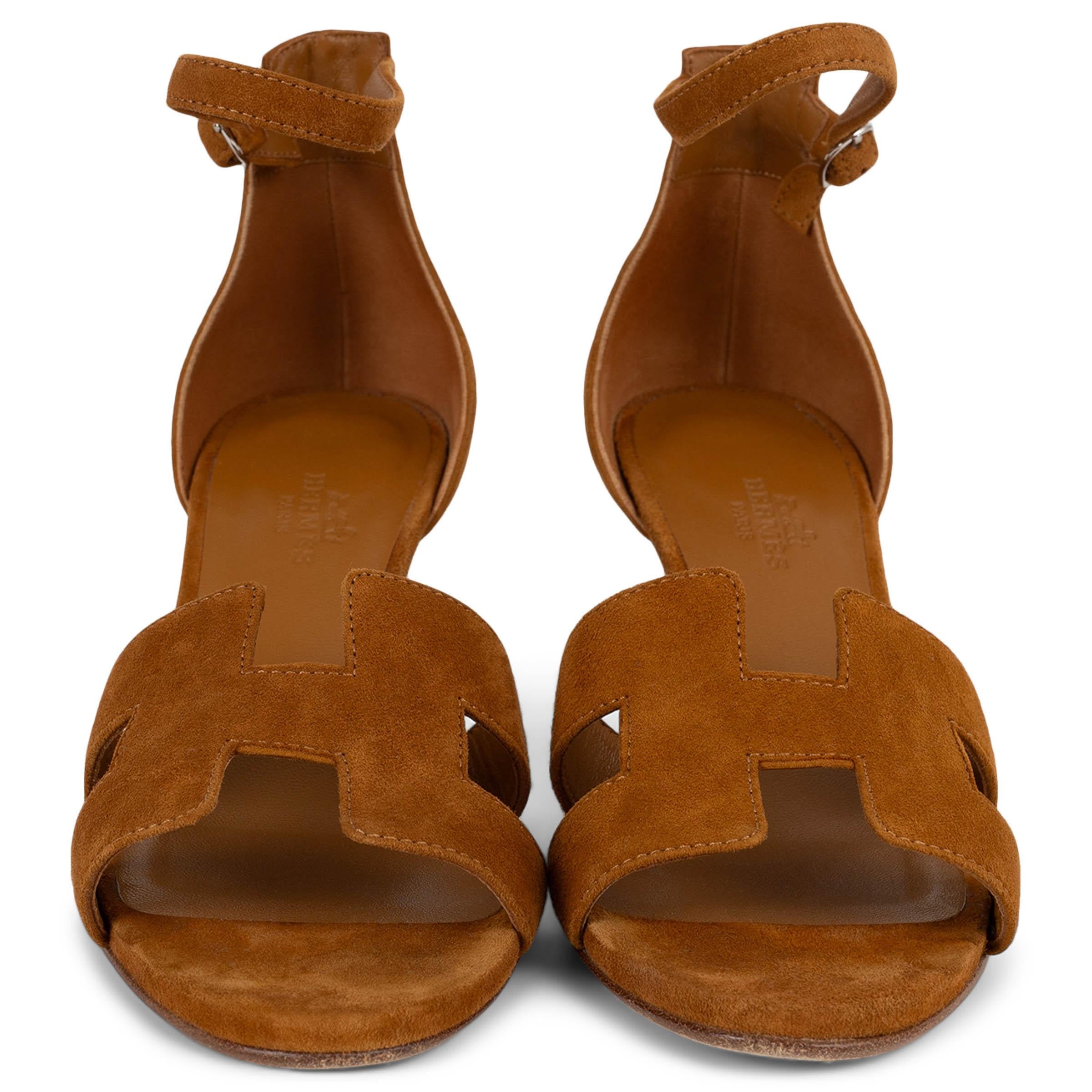 This 100% authentic Hermès Legend sandal is crafted in camel suede and features the Maison’s iconic “H” cut-out across the front. Designed with a stacked leather wedge heel and a slender ankle strap with buckle closure, it offers both elevation and
