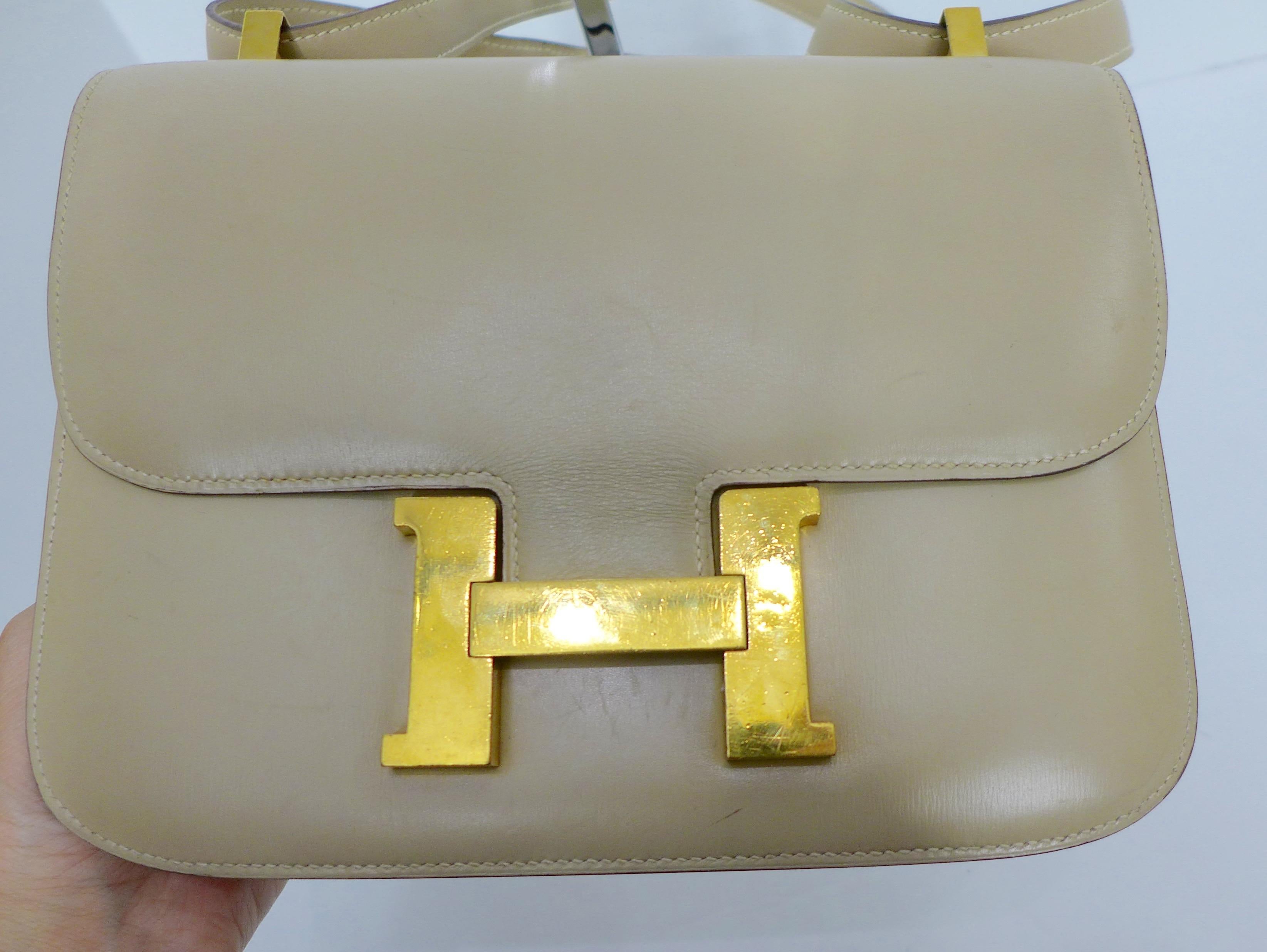 This Hermes leather Constance bag features a gold H closure, gold hardware, and a bone top stitch. Made in France. 

I have adjusted the lighting to show the extent of the interior condition.
The outside snapshot shows the true color of the bag.
It