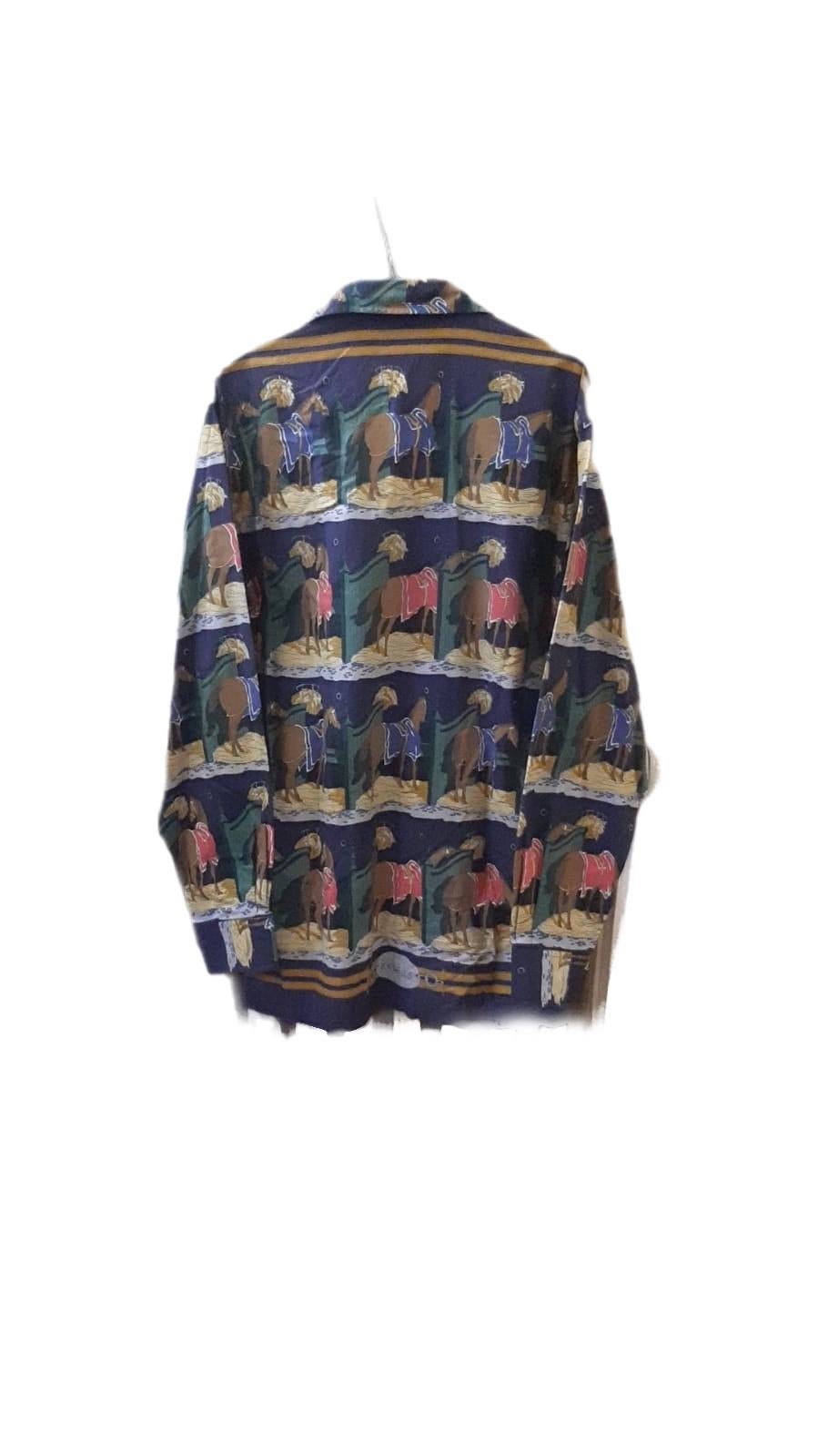 Camicia Hermès Paris autentica, realizzata in Francia, in morbido 100% cotone con l’iconica stampa equestre della Maison.
Il motivo raffigura una scena di scuderie, con cavalli sellati in vari colori, resa nello stile classico dei carré Hermès: