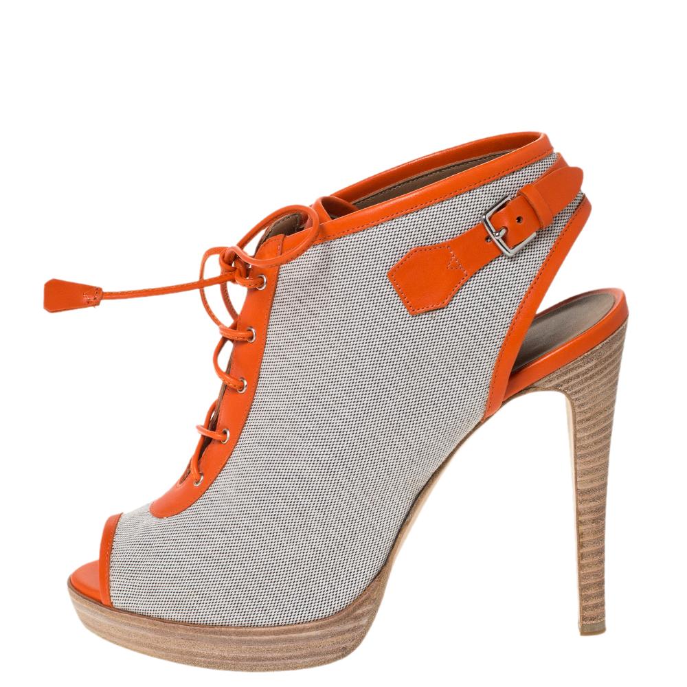 These exquisite booties from Hermes bring a typically seductive feel to the season's bohemian trend. Crafted in grey canvas and orange leather trims, these shoes are elevated on 12.5cm high heels. They feature peep toes, lace-ups on the front, and
