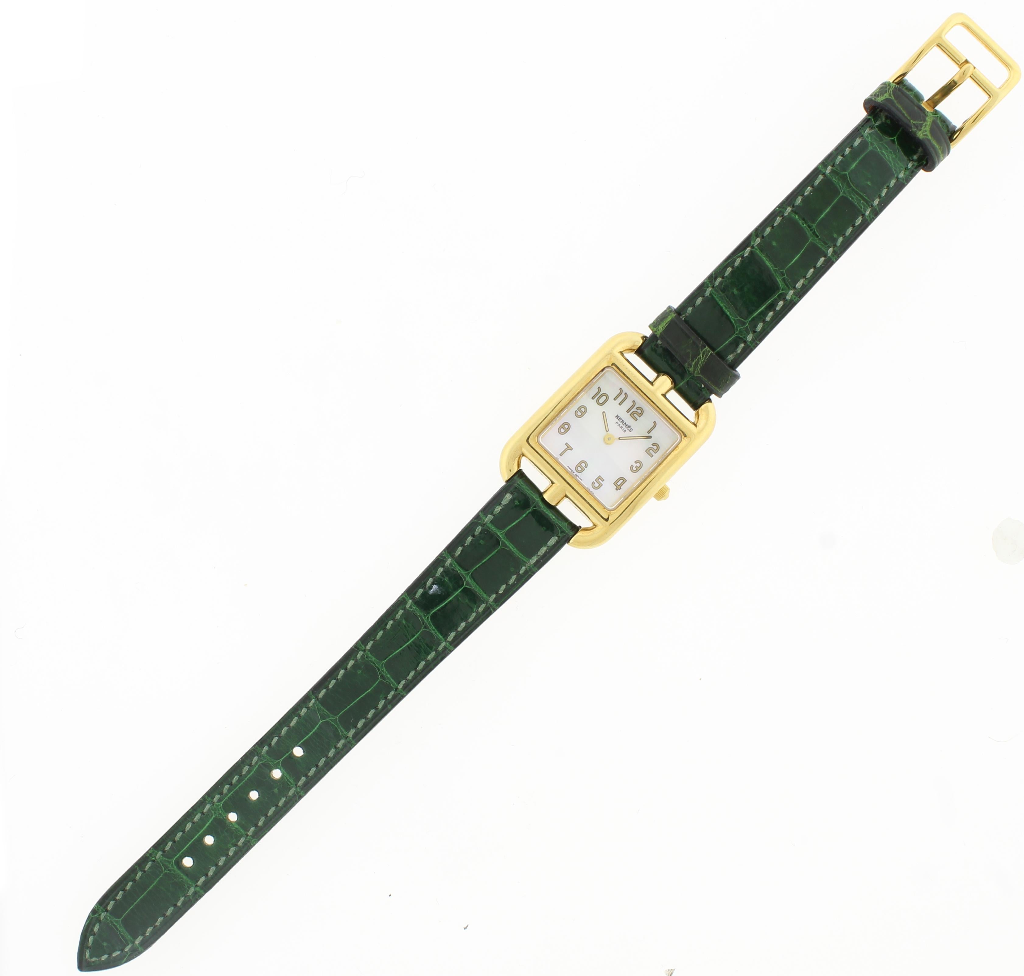 From Hermes, an elegant ladies wrist watch from their cape cod collection
♦ Designer: Hermes
♦  18 karat square case 23mm X 23mm
♦ Smooth green alligator strap with 18 karat yellow gold tang/pin buckle
♦ Solid screwed-in case back adorned with the
