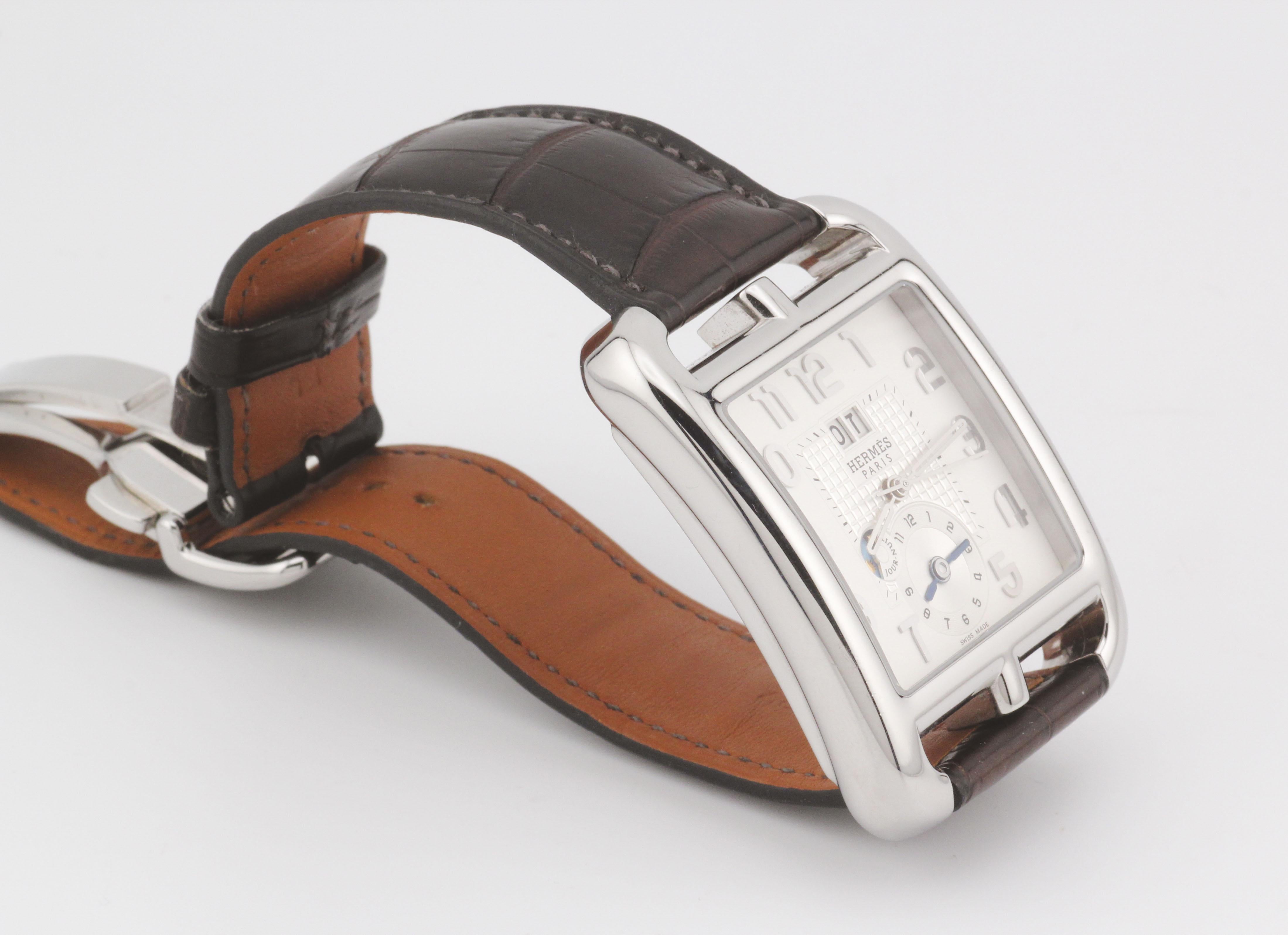 Die Hermès Cape Cod TGM CD6.910 Automatic Grand Date GMT ist ein eleganter Zeitmesser, der die meisterhafte Handwerkskunst und das Design der Marke verkörpert. Diese raffinierte Uhr verfügt über ein schlankes, rechteckiges Gehäuse, das vom