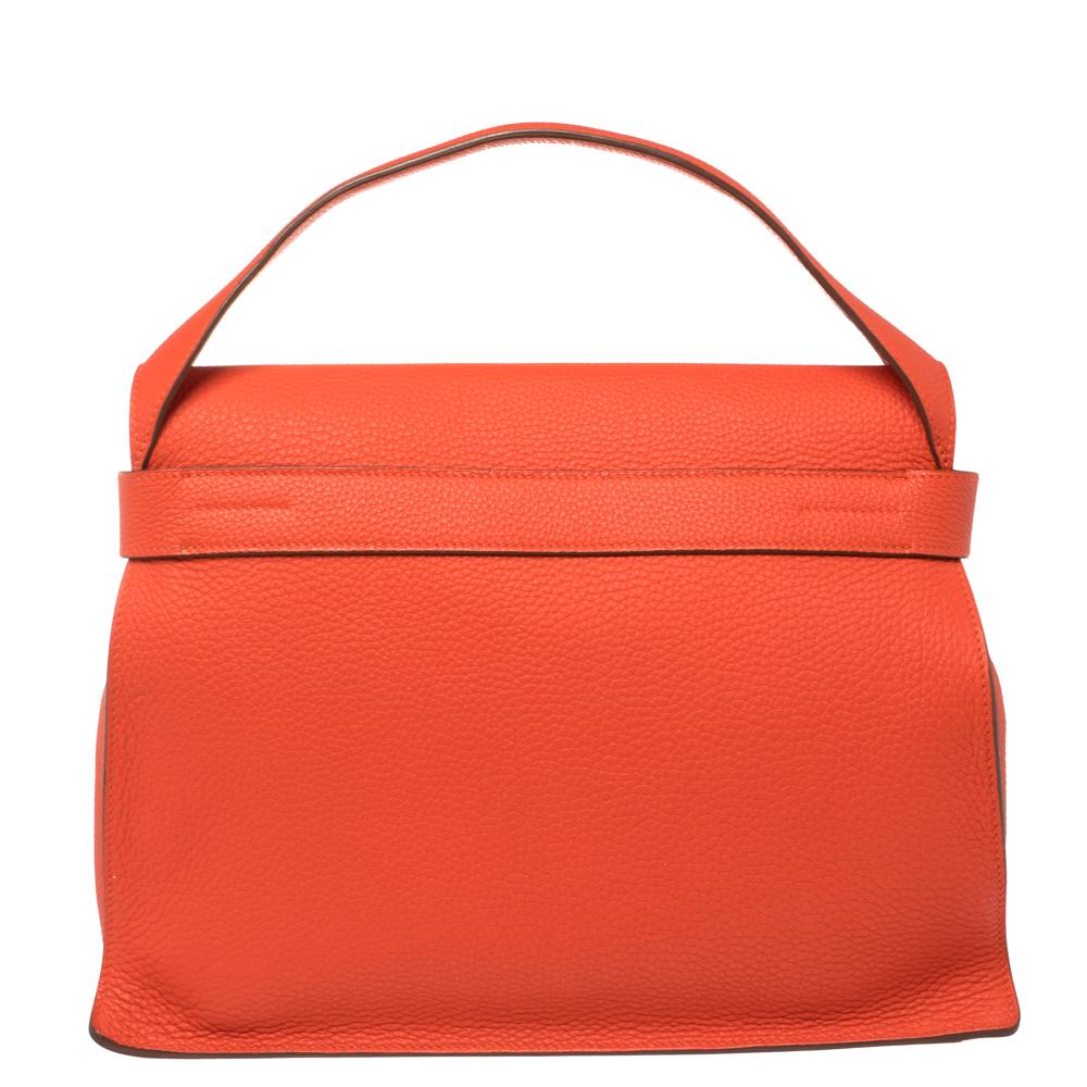 This Hermes bag is anything but ordinary! It has been crafted from capucine taurillion Clemence leather and creatively styled with an adjustable buckle belt closure on the front. It boasts of a single top handle and a leather-lined interior that