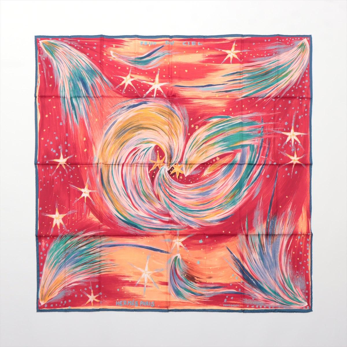 The Hermès Carré 90 Feux Du Ciel Scarf in red is a striking and luxurious accessory that reflects the brand's dedication to art and craftsmanship. Made from premium silk, the scarf features a dynamic design inspired by celestial fireworks, with