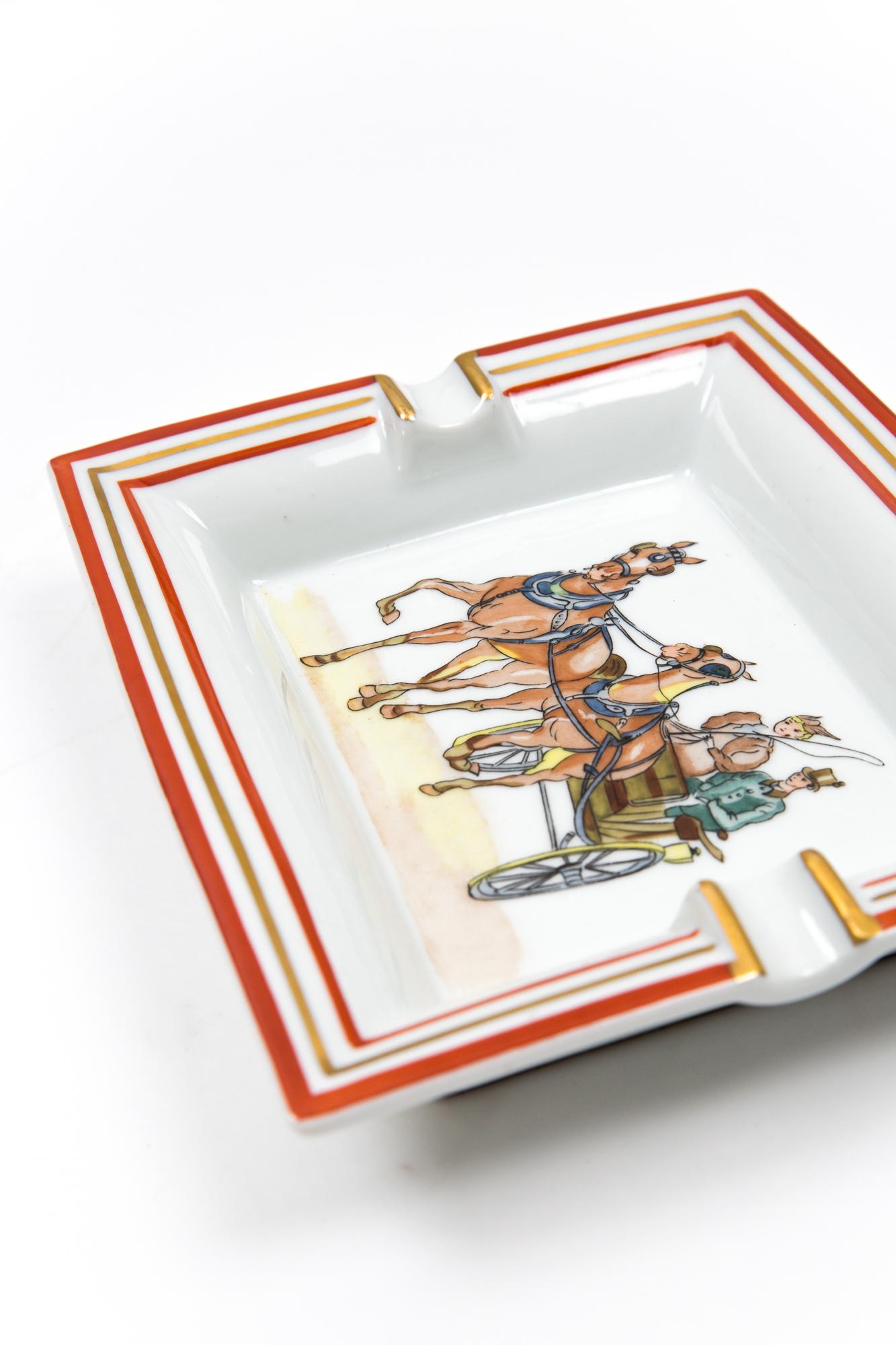 Hermès horse-print porcelain organizer or Ashtray featuring a a carriage, a gold brush finishing, a under leather bottom, a Hermes gold-tone side signature.  
Circa 1980s 
In good vintage condition. 
Maxi Length 7.4in (19cm)
Maxi height 6,3in.