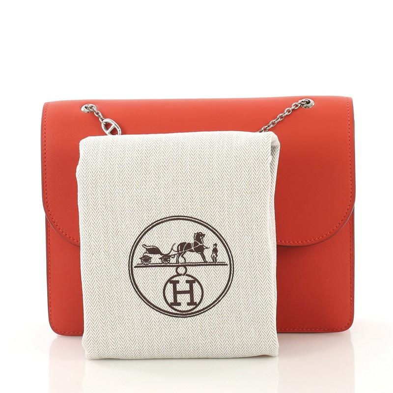 This Hermes Catenina Handbag Swift Small, crafted in Capucine red Swift leather, features chain link strap, farandole charm details, and palladium hardware. Its snap closure with chain links opens to a Capucine red Swift leather interior with slip