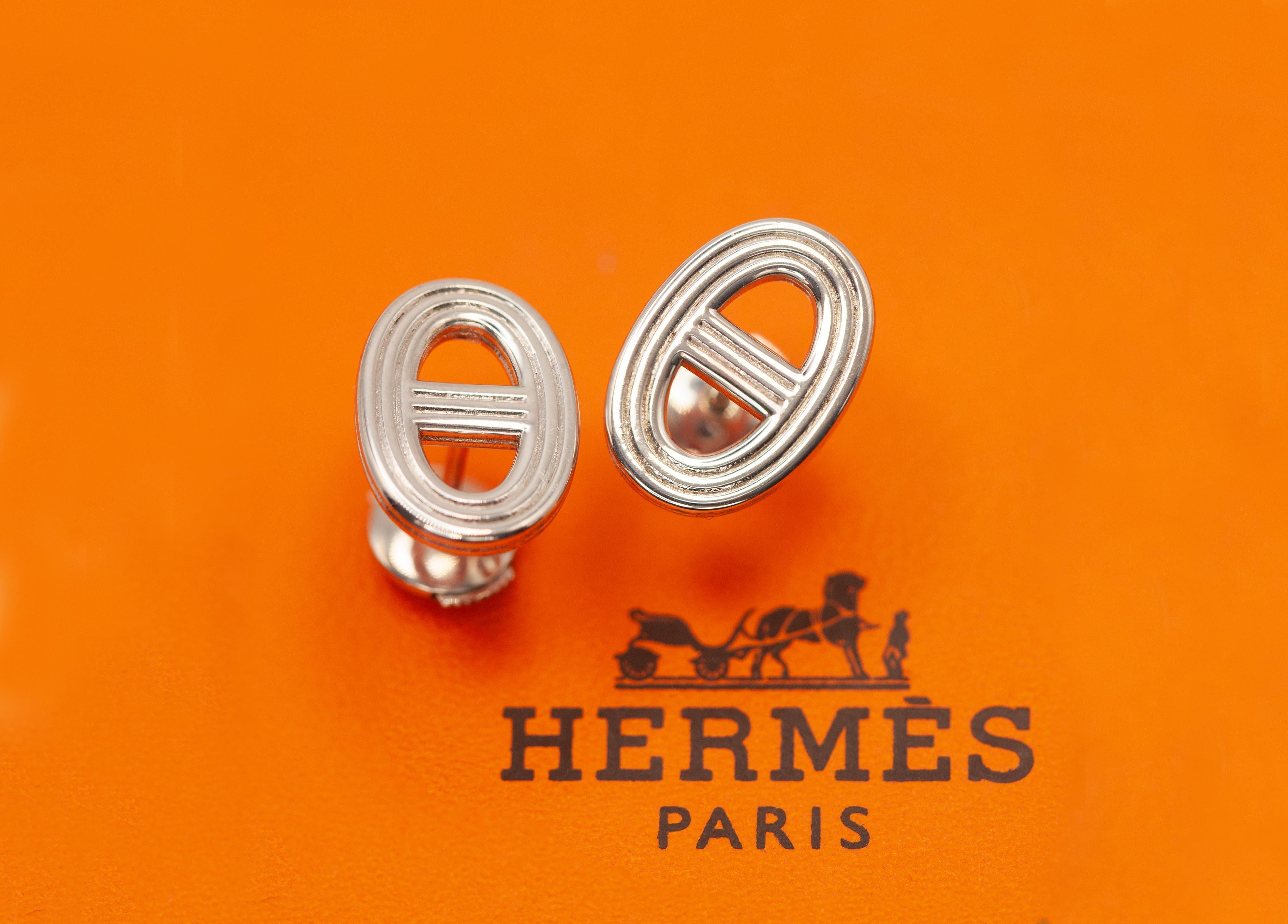 Estos pendientes Hermès Chaine d'Ancre 24, icónicos y elegantes sin esfuerzo, están fabricados en plata de ley y lucen el motivo de cadena de ancla característico de la casa. Con una atrevida silueta ovalada y detalles de barras horizontales, este