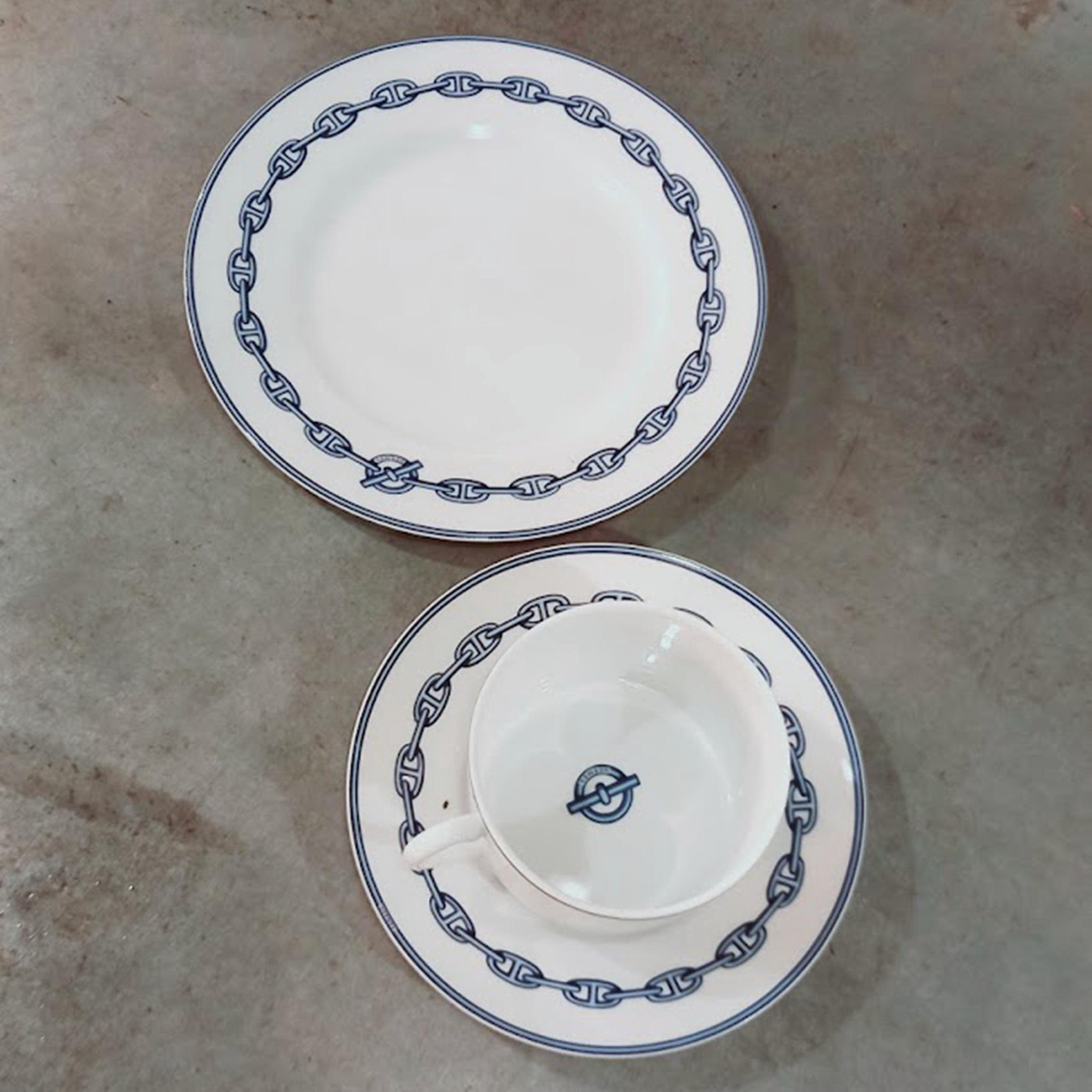 A porcelain breakfast cup (34 cl), saucer and side plate setting in the Chaine d'Ancre pattern in grey by Hermès. Signed, made in France, and produced from 1997-2017.

Hermès' signature chain link as a border against pristine white porcelain.