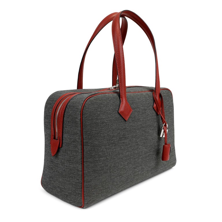 This authentic Hermès Charcoal Canvas Victoria II Satchel is in pristine condition.  Hand sewn by skilled artisans, this beautiful daily bag from Hermès is a more affordable cousin to the Birkin or Kelly. 
Dark charcoal grey Toile fabric rectangular