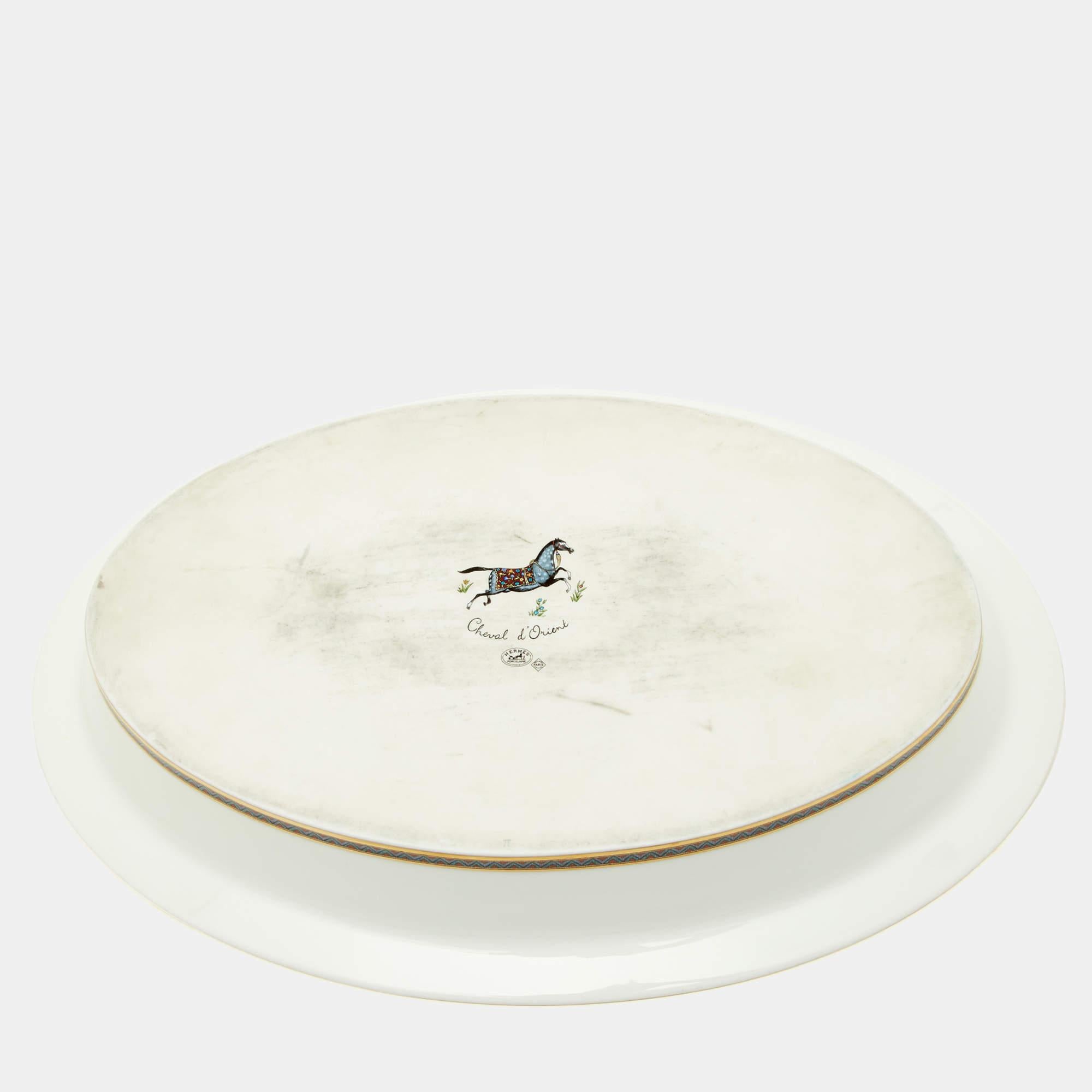 The Hermès Cheval d'Orient vegetable dish is an exquisite piece of tableware. Crafted from fine white porcelain, it features a delicate printed design inspired by oriental motifs. With its elegant and timeless aesthetic, this dish adds a touch of