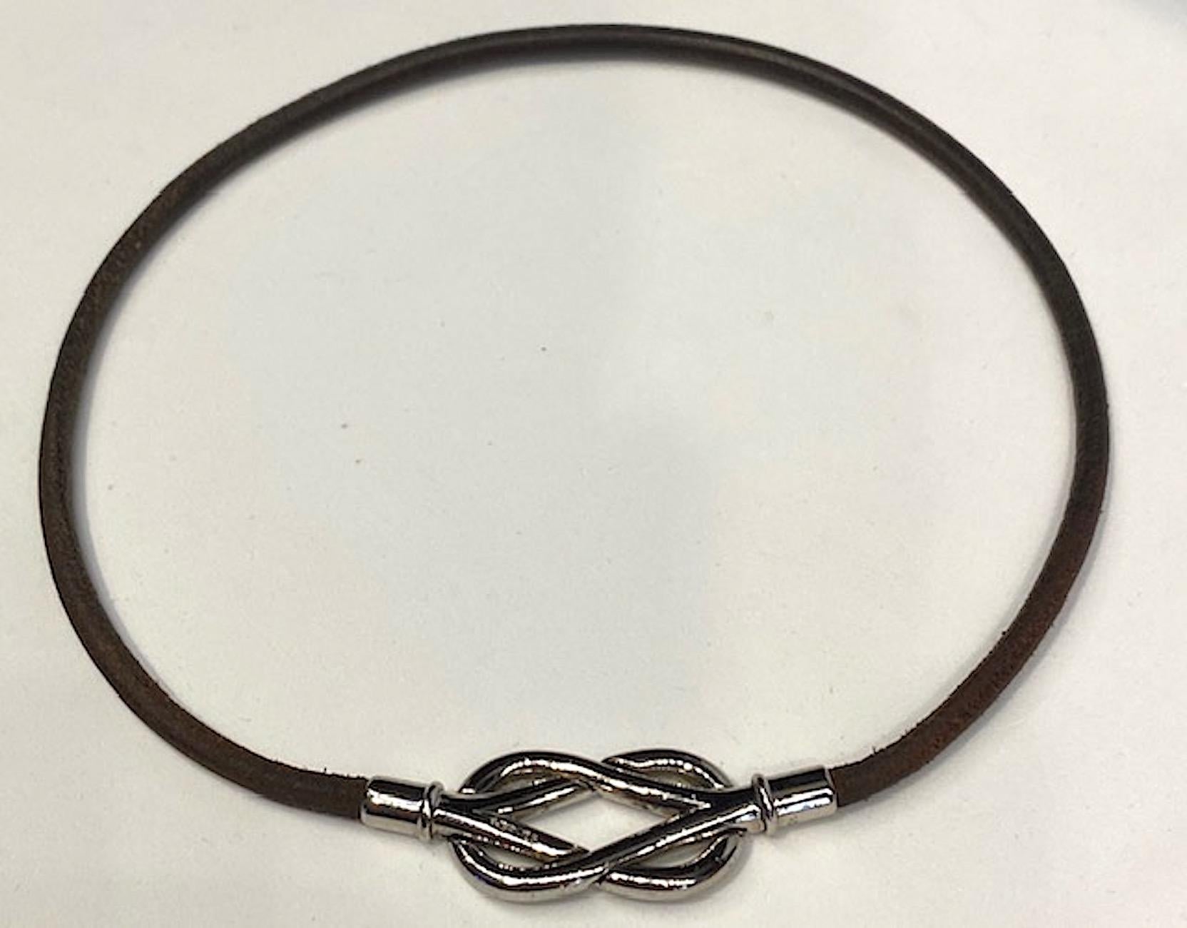 Hermes chocolate brown color leather cord with rhodium plate square knot clasp. Knot is 1.38 inches wide and .75 of an inch high not including the rhodium end pieces that hold the leather cord ends. With the rhodium end pieces the clasp is 2 inches