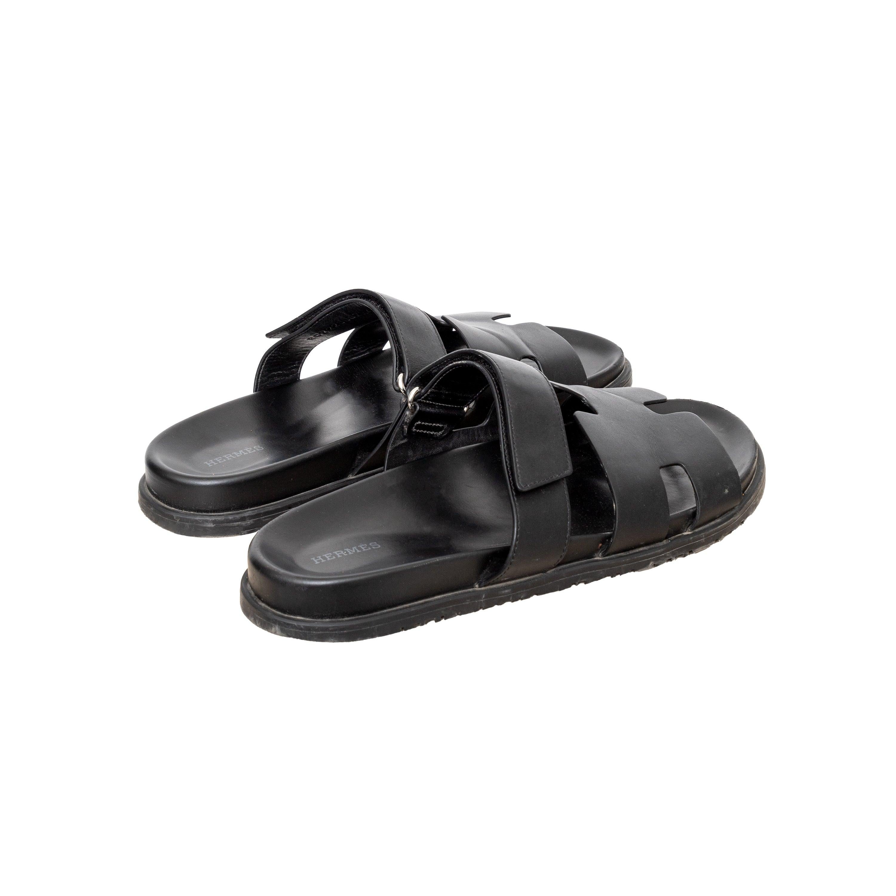 Crafted from black leather, these Hermès sandals feature an adjustable strap, anatomical rubber sole for support, and the Maison's iconic 'H' cut, inspired by the islands of Aphrodite.
 Inclusions: dust bag.  
 Measurement: Insole Length:29;Heel:3 
