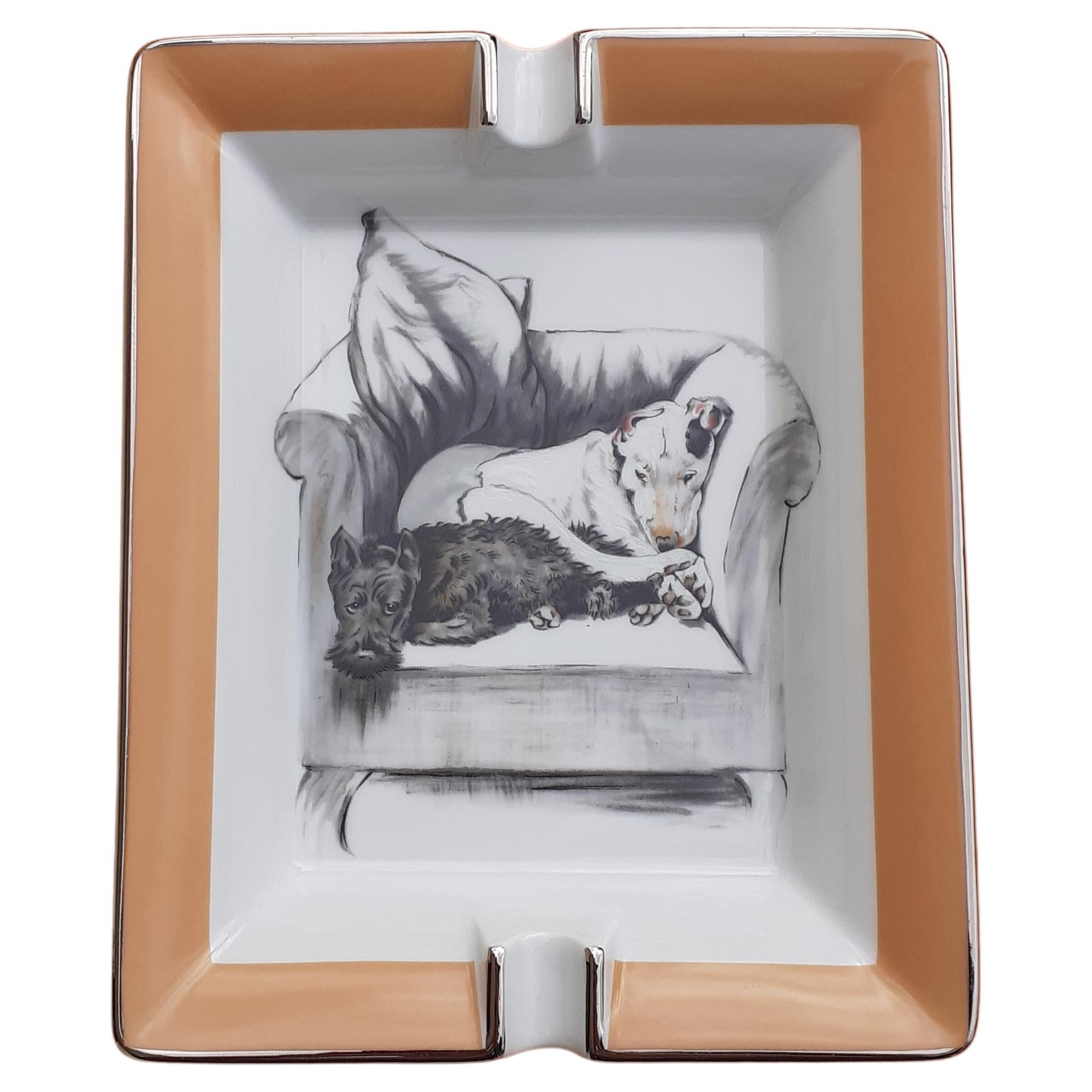 Rare and Adorable Authentic Hermès Ashtray

Print: 2 dogs napping on an armchair

Drawing from Cecil Aldin

Made in France

Made of printed porcelain and silvery edges

Camel color leather at bottom

Colorways: White, Beige, Grey

The white dog has