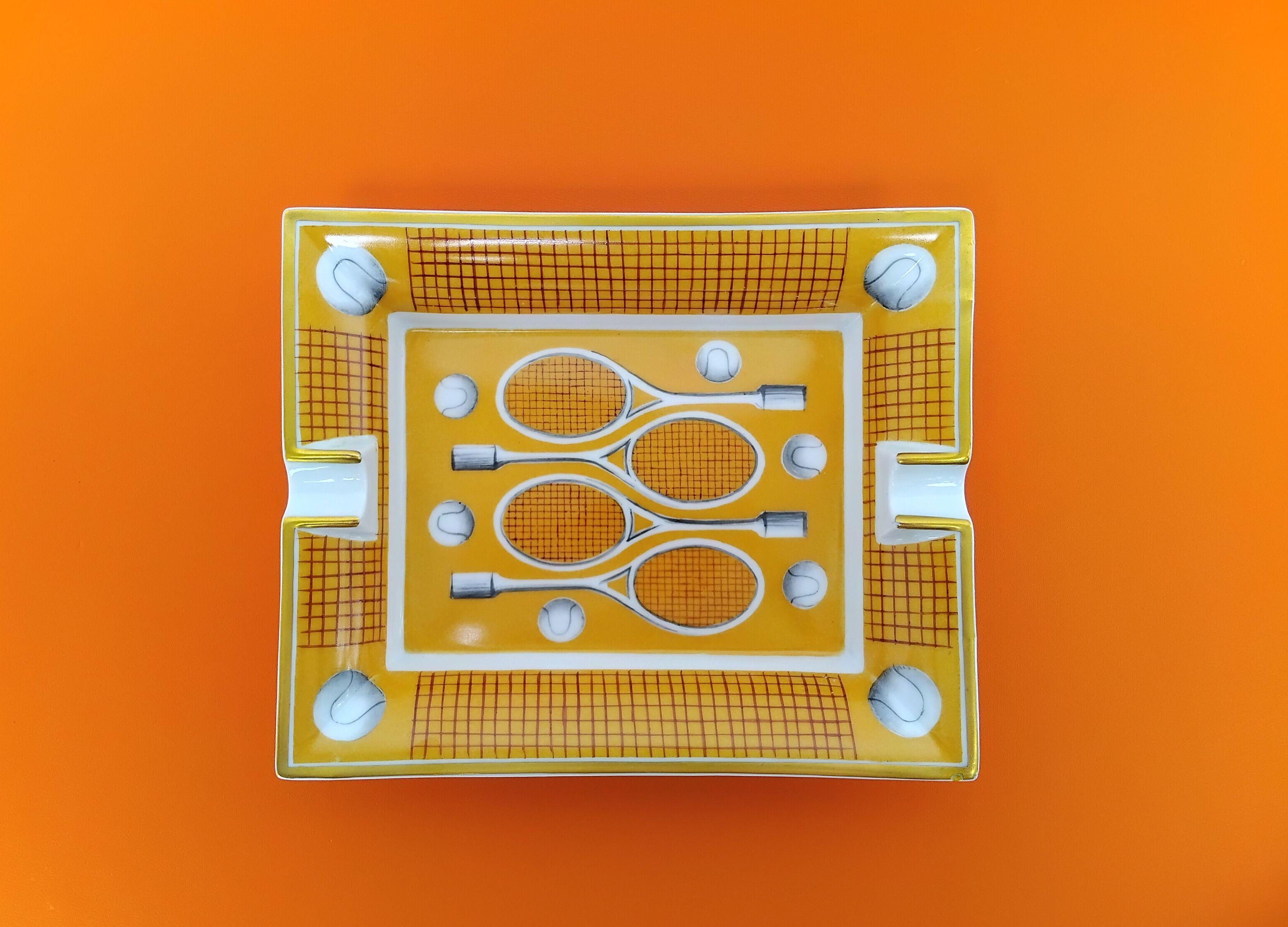 Extremely Rare Authentic Hermès Ashtray

Print: Tennis Racquets, balls, nets

Made in France

Vintage item

Made of porcelain, edges gilded with fine gold

Bottom covered with fauve color suede leather

Colorways: Yellow, White, Brown,