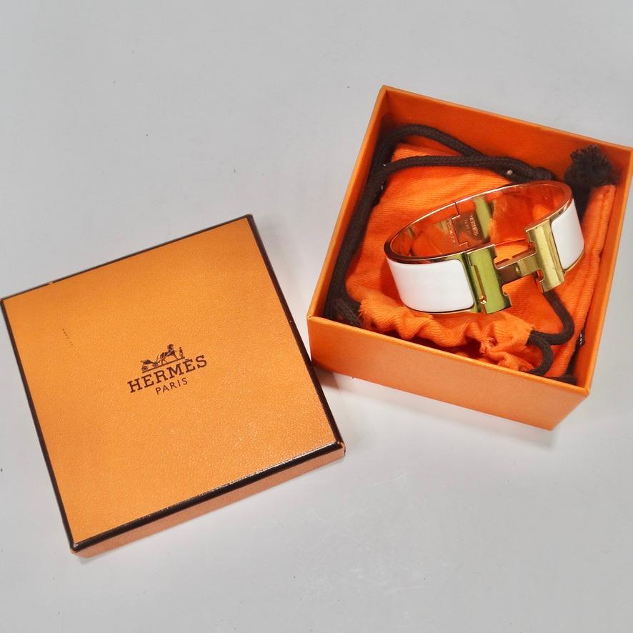 Get your hands on this absolutely iconic Hermes Clic Clac 'H' bracelet! Gold plating is accompanied by white enamel and signature Hermes 'H' motif at the center. Classic bangle style with a snap closure hence the 'clic clac' name. This is such a