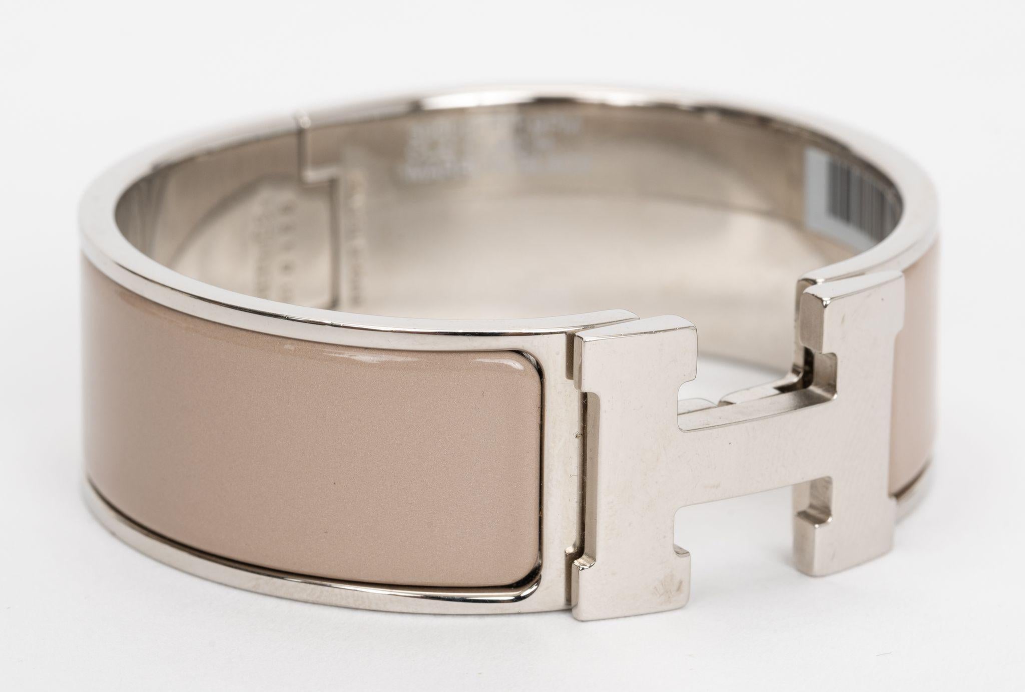 La pulsera Hermes Clic Clac H esmaltada en Marron Glace, es una pulsera clásica pero muy moderna. Presenta una banda chapada en paladio y una 