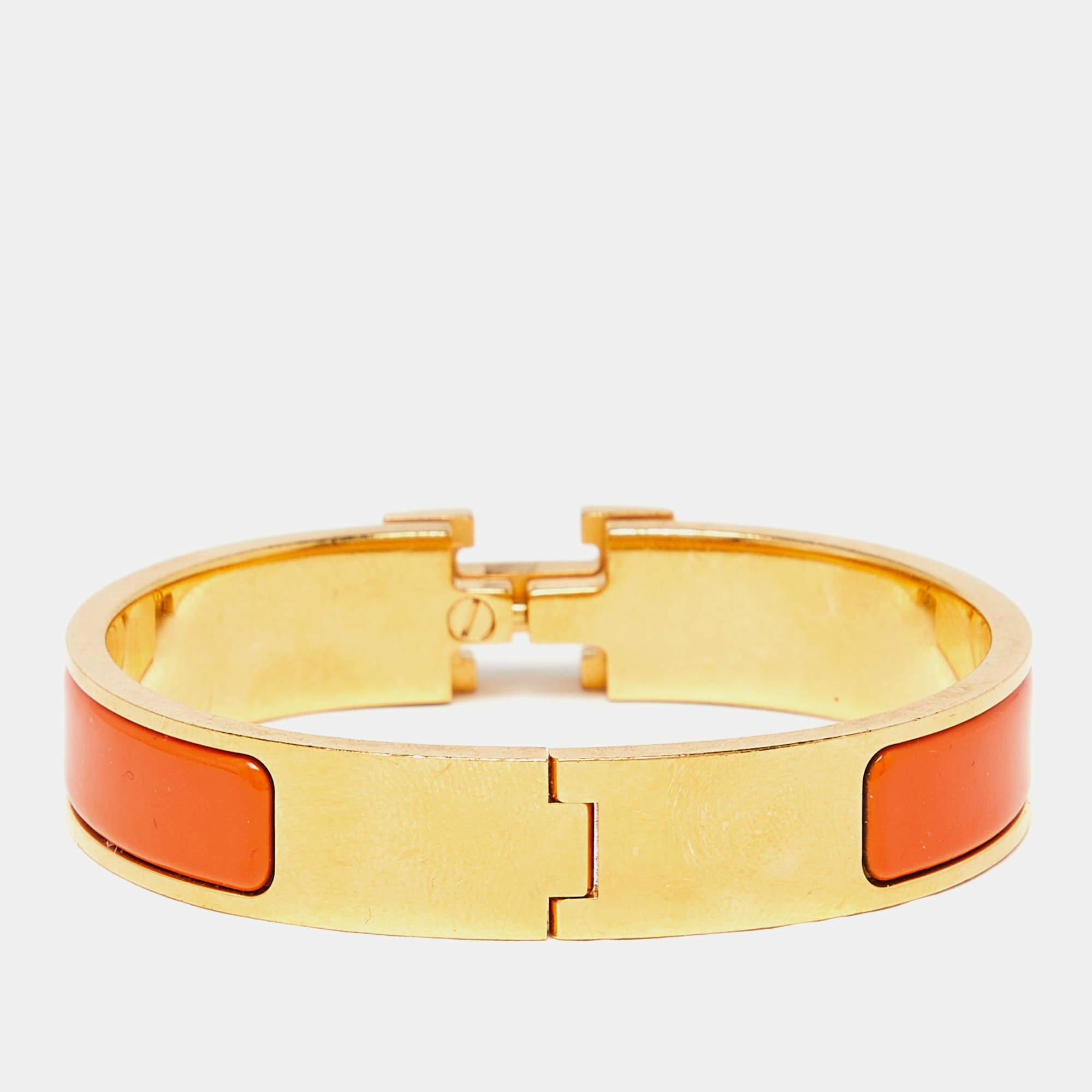 The Hermès Clic Clac H bracelet is an exquisite piece of jewelry. It features a glossy white enamel band with a prominent gold-plated H-shaped clasp, creating a striking contrast. This luxurious and elegant accessory embodies timeless style and