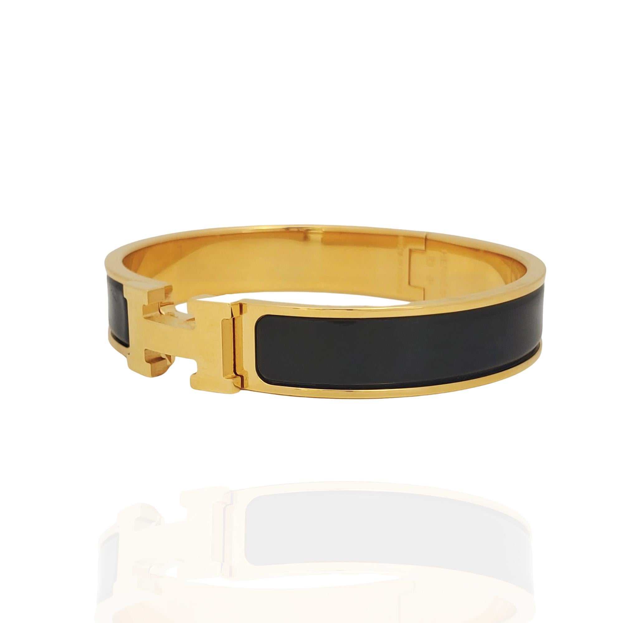 Authentic Hermès Clic H narrow bracelet crafted in black enamel with gold-plated hardware. The bracelet measures .47 inches in width with an internal circumference of 7 inches.  Signed Hermès, Made in France, with Q stamp and hallmark.  Bracelet is