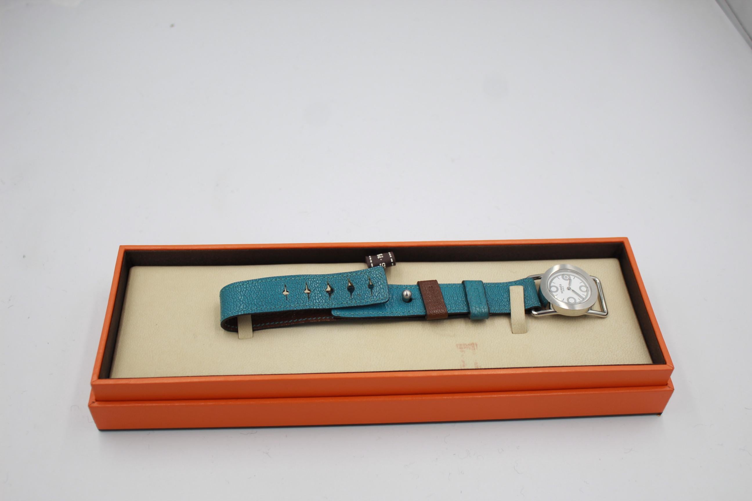 Hermès Barenia ronde watch with a leather strap, one side blue and one side chocolate coloured. The bracelet is adjustable and can be worn in different sizes. 
Good condition, some signs of wear on the leather strap.
Sold in its original box

