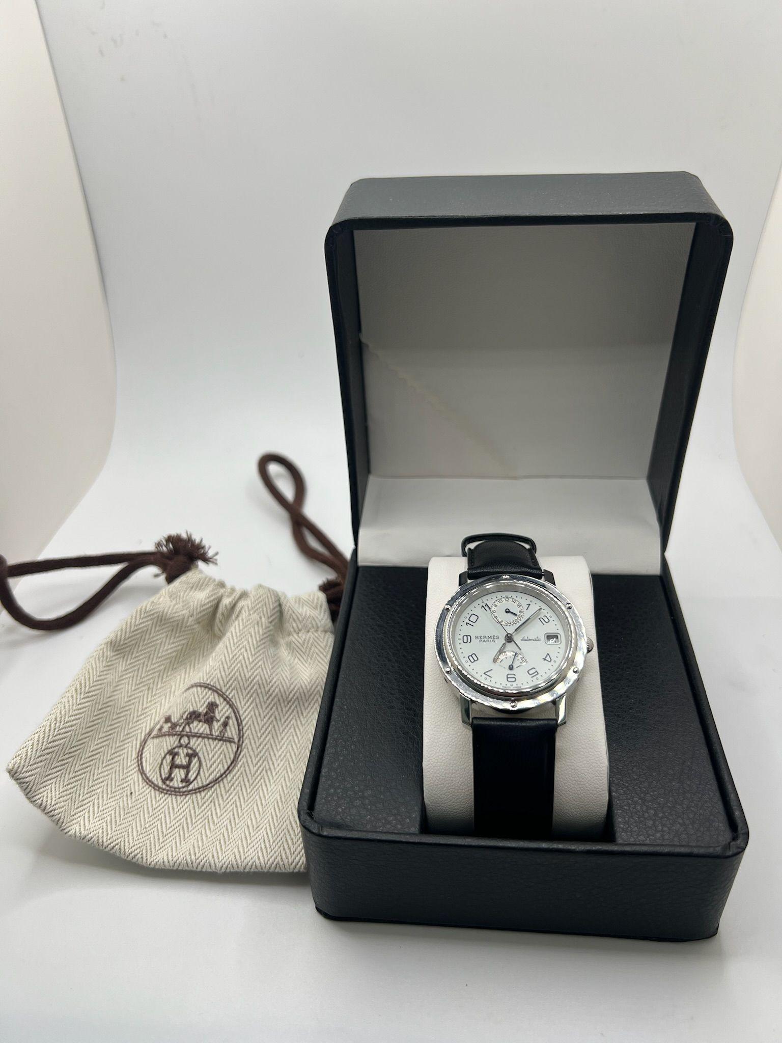 Questo Hermès Clipper referenza CL5.710 è un raffinato orologio automatico che unisce precisione ed eleganza senza tempo. La cassa in acciaio inossidabile da 36 mm presenta una lunetta delicatamente incisa e un quadrante bianco e pulito con numeri