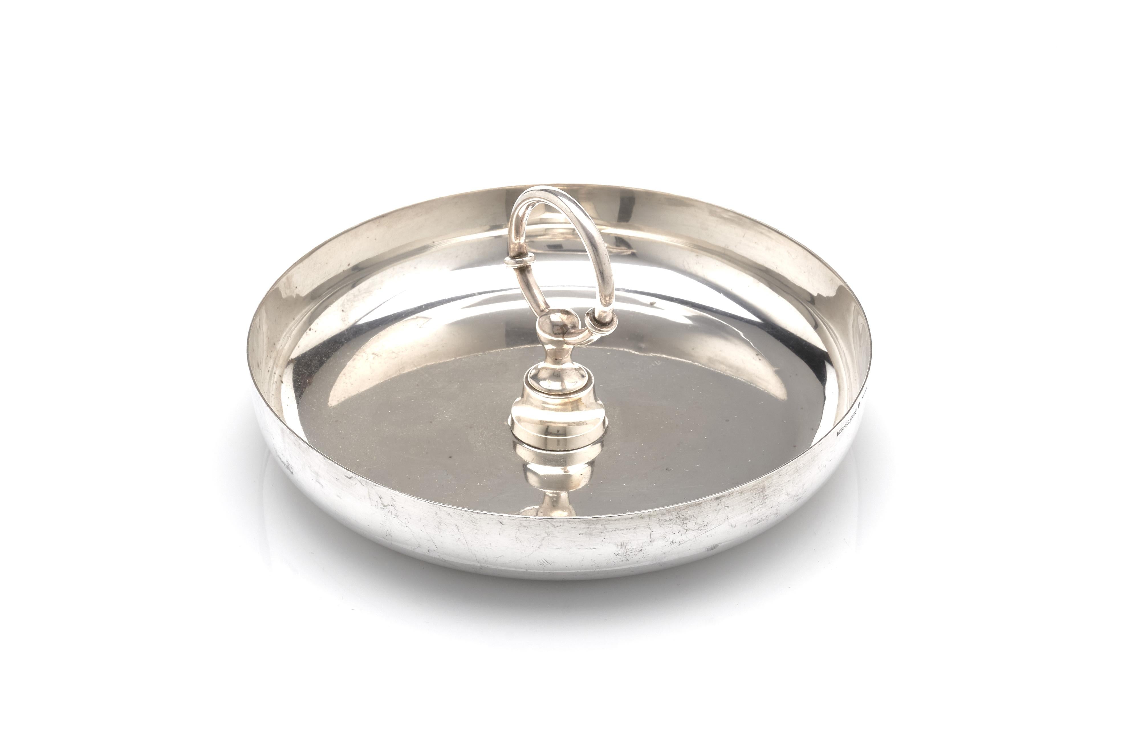 A fine silver plated coffee table dish or centerpiece by Hermès. Finished with a horse-bit handle in the center, this will provide luxurious storage for anything on your coffee table. 

Marked on bottom, 1970s.