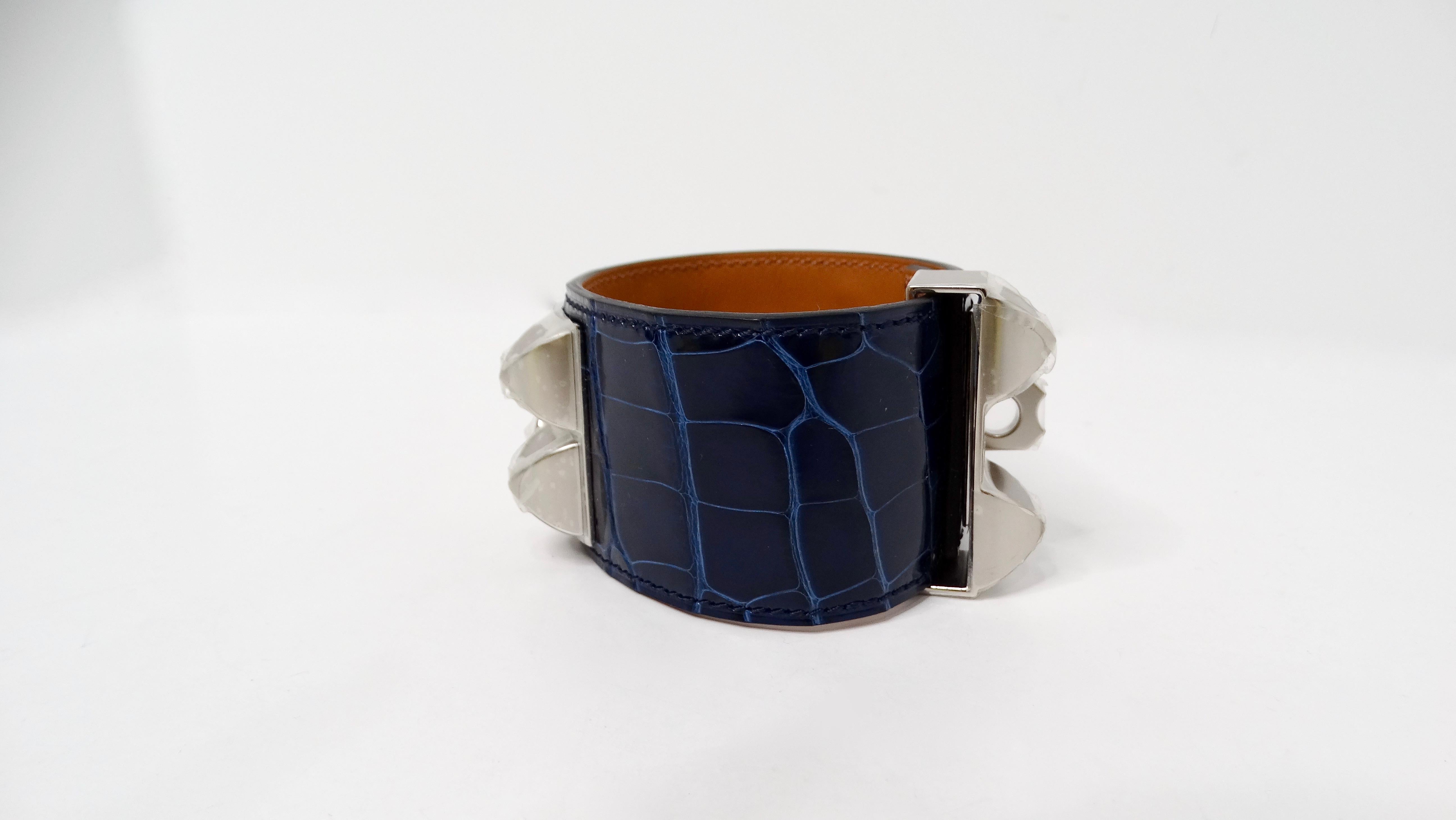 Le magnifique bracelet manchette en alligator plaqué palladium Collier De Chien Bleu Saphir Hermes est une pièce d'exception qui incarne le luxe et la sophistication. Fabriquée en cuir d'alligator Mississippiensis, cette manchette est réputée pour