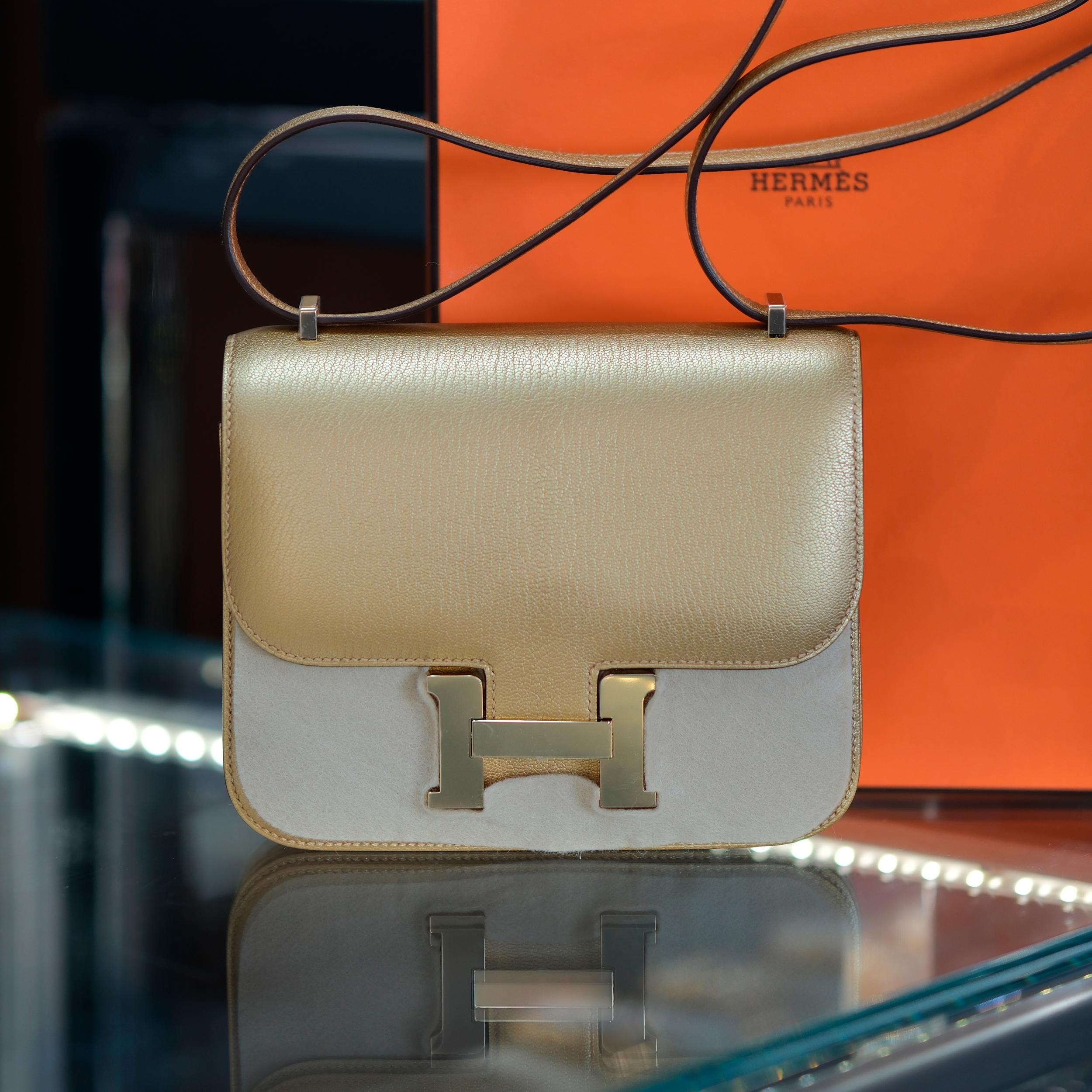 Ce modèle Hermès Constance 18 est réalisé en cuir Dore Chevre Chamkilight et doté d'élégantes ferrures en permabras. Il présente des surpiqûres ton sur ton, le fermoir en 