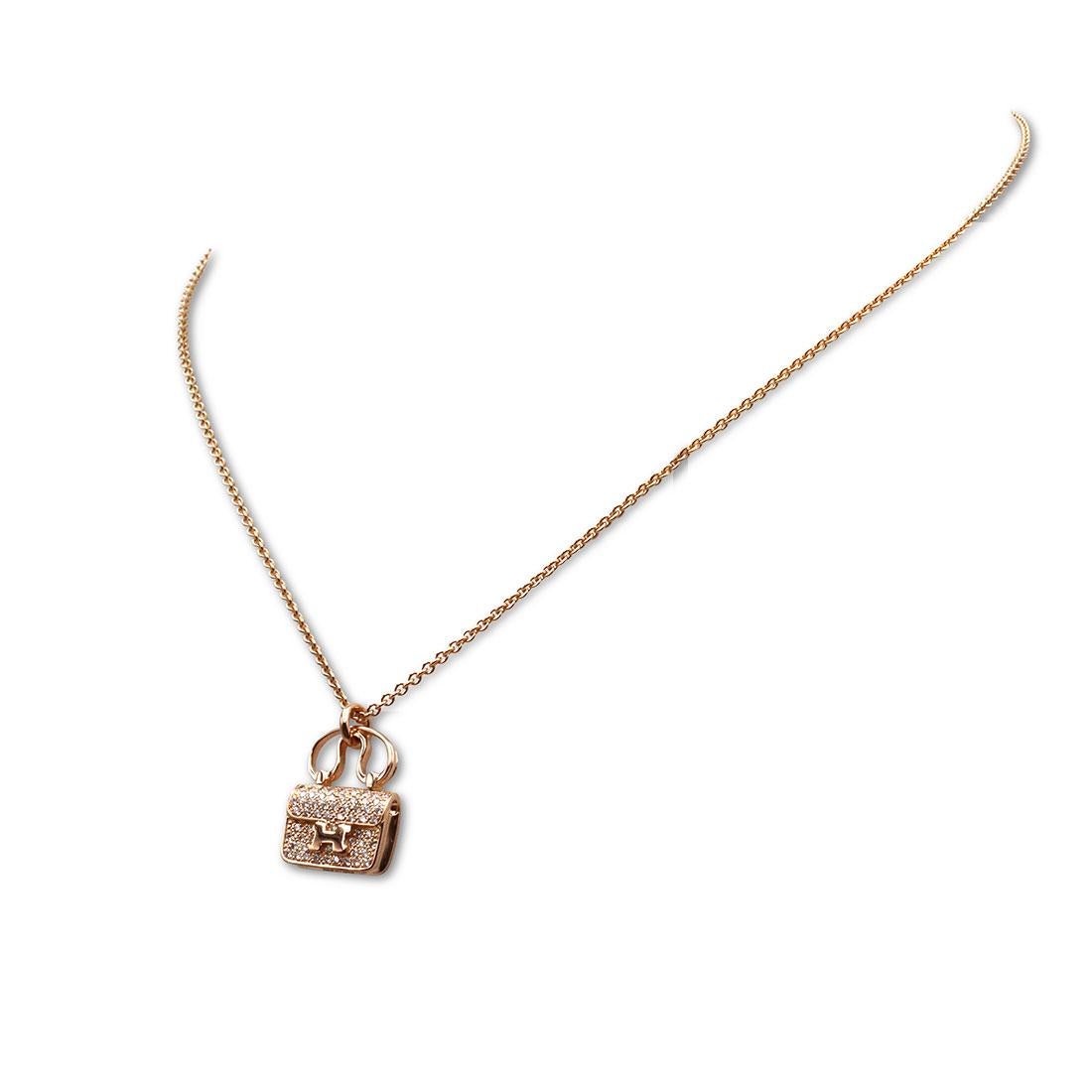 Authentic Hermès Constance Amulette pendant necklace crafted in 18 karat rose gold. The pendant is designed as an Hermès Constance handbag set with round brilliant cut diamonds carrying an estimated .29 total carat weight. The pendant hangs from an