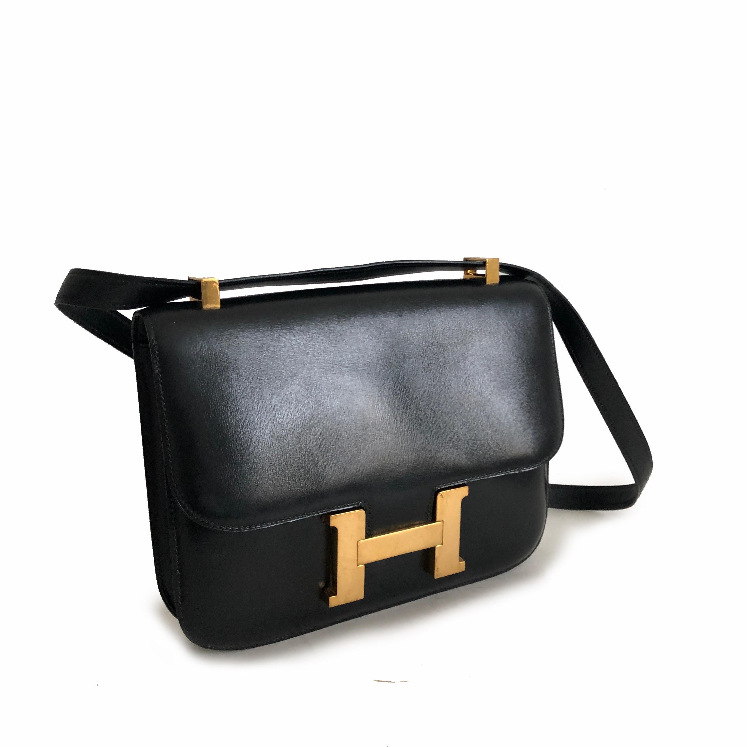 Hermes Constance Bag 23cm in Black Box Leather. Fully-lined with one zipper pocket. Adjustable strap allows wear on shoulder or by hand. Preowned/vintage with some signs of wear: light scratches/color loss to areas of hardware; fingernail scratches