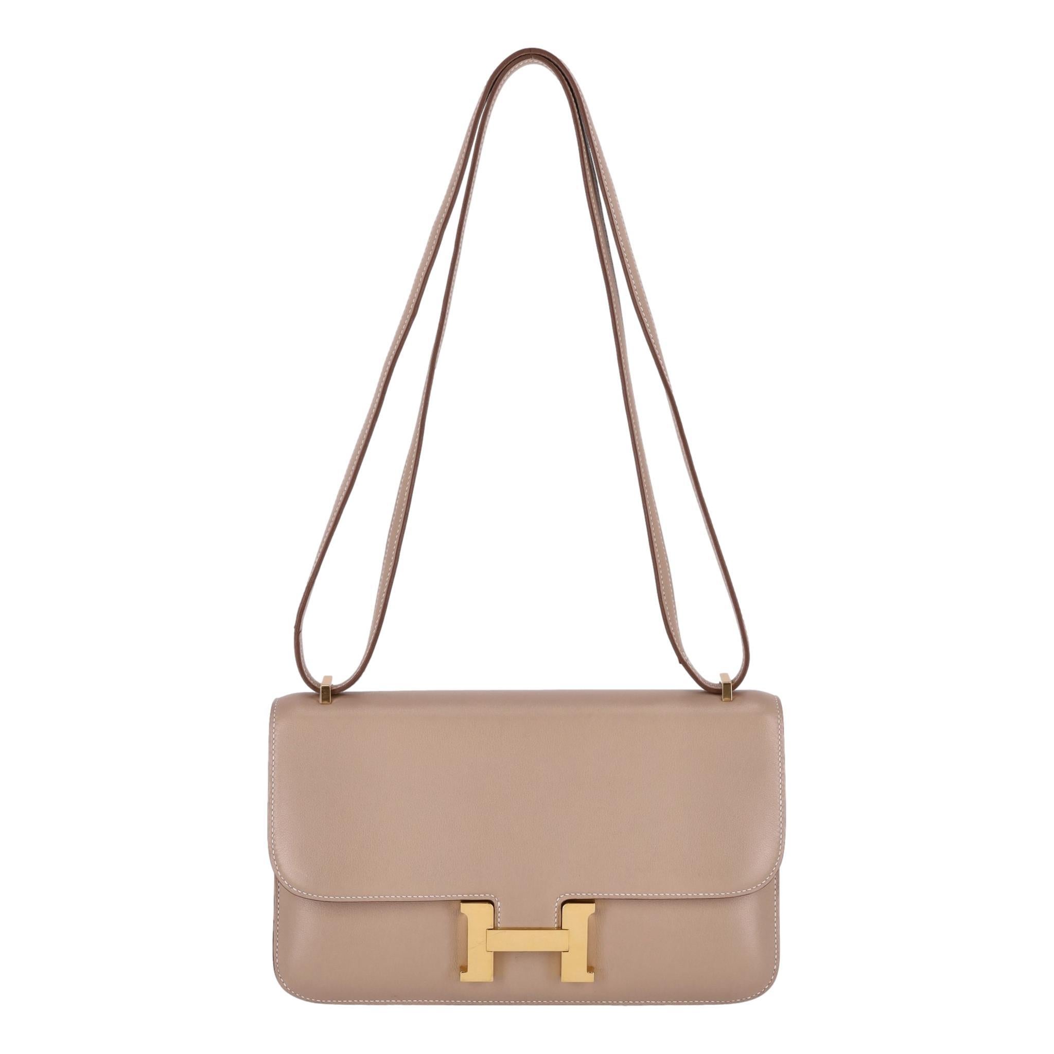 Hermes Constance Elan Crossbody Bag

Crossbody bag crafted in smooth etoupe Swift leather with gold hardware.

Detailed with front flap and signature 'H' shaped clasp closure.

Featuring adjustable crossbody shoulder strap and contrasting white