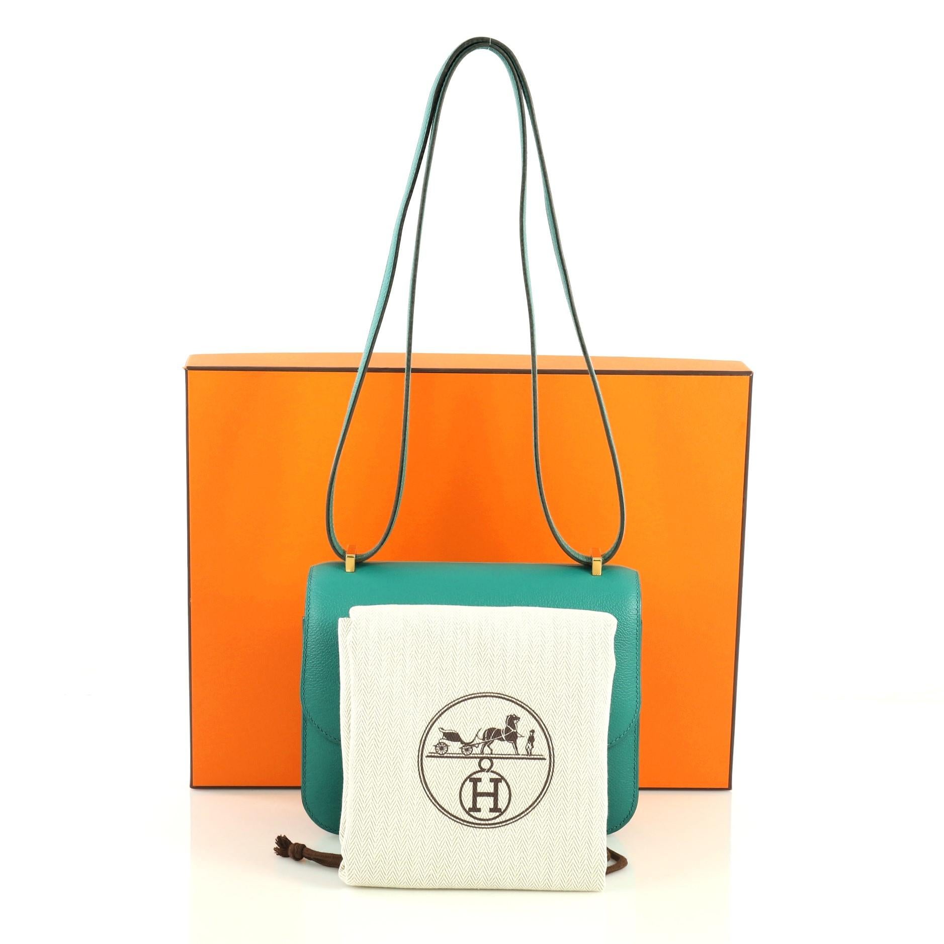 This Hermes Constance Handbag Evercolor 18, crafted from Vert Verone green Evercolor leather, features a long leather strap and gold hardware. Its push-lock closure opens to a Vert Verone green Agneau leather interior with two open compartments and