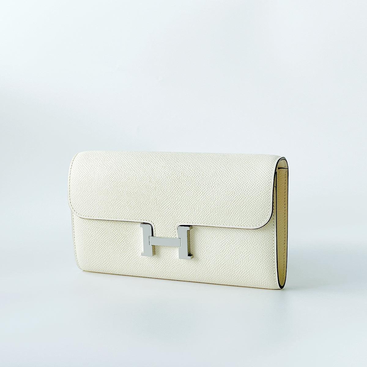 A beautiful Constance Long To Go Wallet In Nata And Gold Hardware. This wallet has a strap making it perfect as a small bag. Inside has 4 credit card slots, 2 pockets, 1 zipped change purse and an exterior pocket. 

Brand: Hermès
Colour: