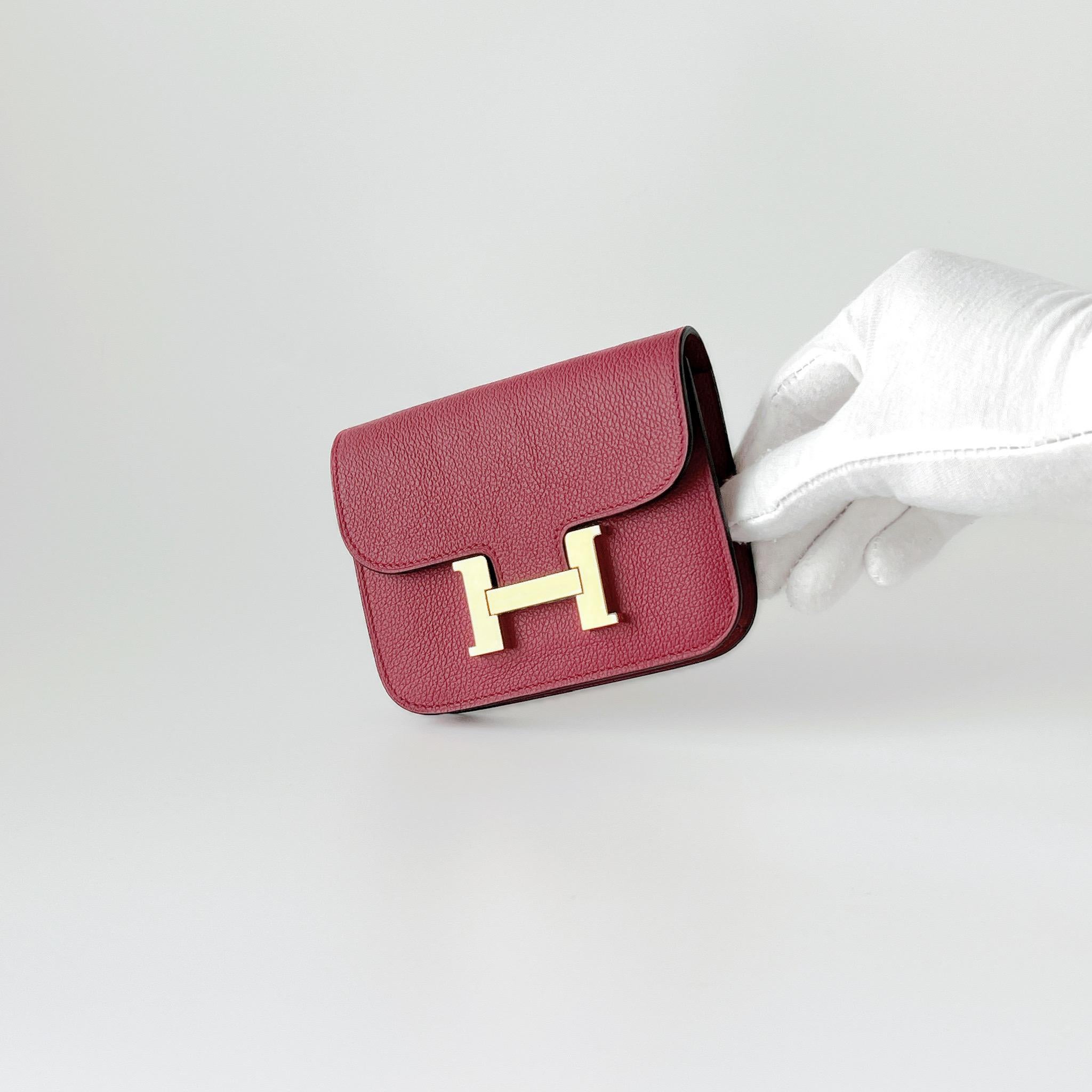 Hermes Constance Slim Wallet In Rouge Grenat With Gold Hardware. This classic wallet comes in a dark red lipstick coloured red known as Rouge Grenat, which is complimented by Gold Hardware. The Constance Slim Wallet is typically a belt bag which can