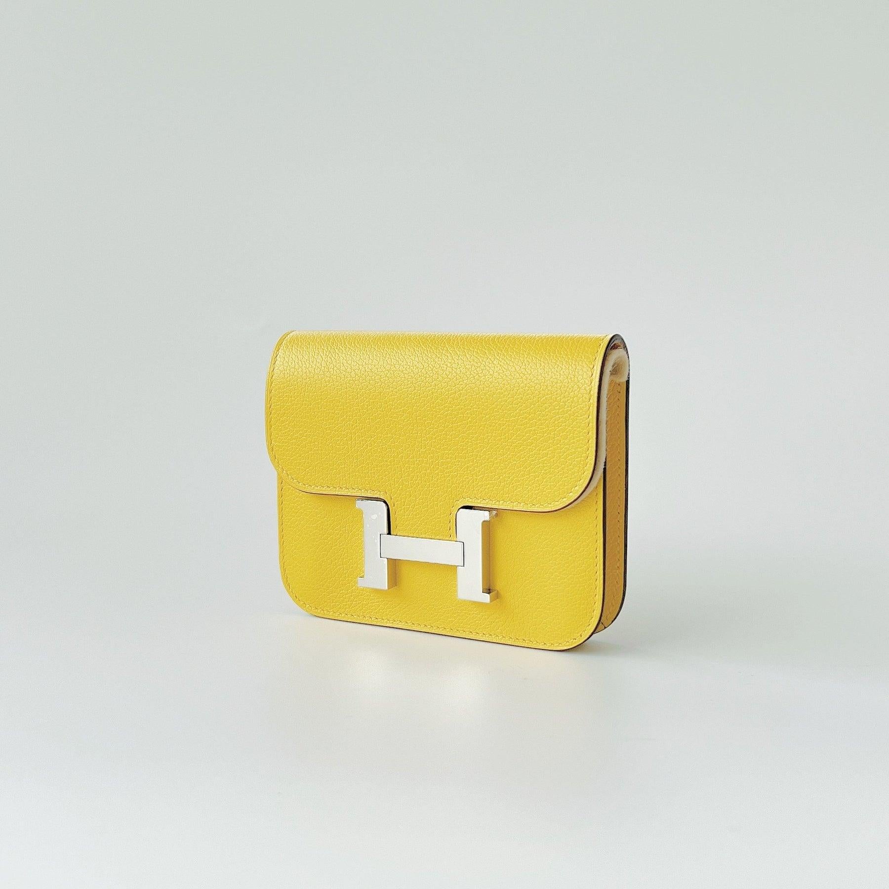This beautiful Hermès Constance Slim Wallet is in Jeune De Naples (Yellow) with Silver plated hardware. Included is a removable wallet that can be used as a change purse. There is also 2 credit card slots. In the rear is a belt loop which can fit