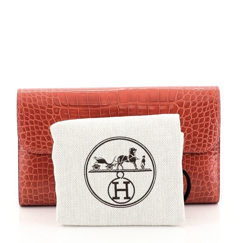 This Hermes Constance Wallet Shiny Alligator Long, crafted from genuine Geranium red Shiny Alligator, features a frontal constance 