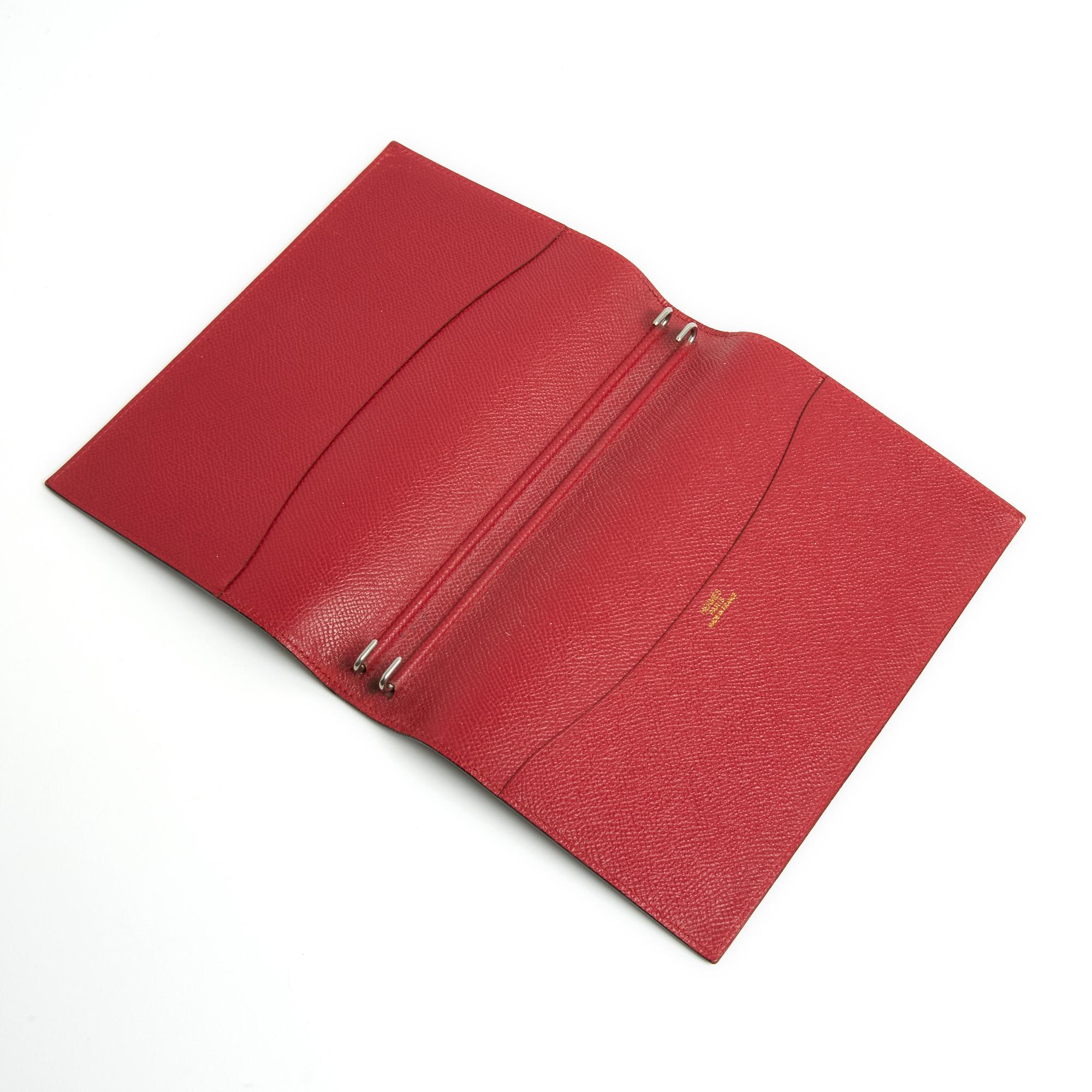 Couverture d'agenda Hermès Globe Trotter en cuir noir souple et légèrement grainé à l'extérieur, intérieur en cuir rouge avec deux grandes poches de rangement et des paires d'agrafes en métal argenté pour maintenir le carnet, l'agenda, le carnet