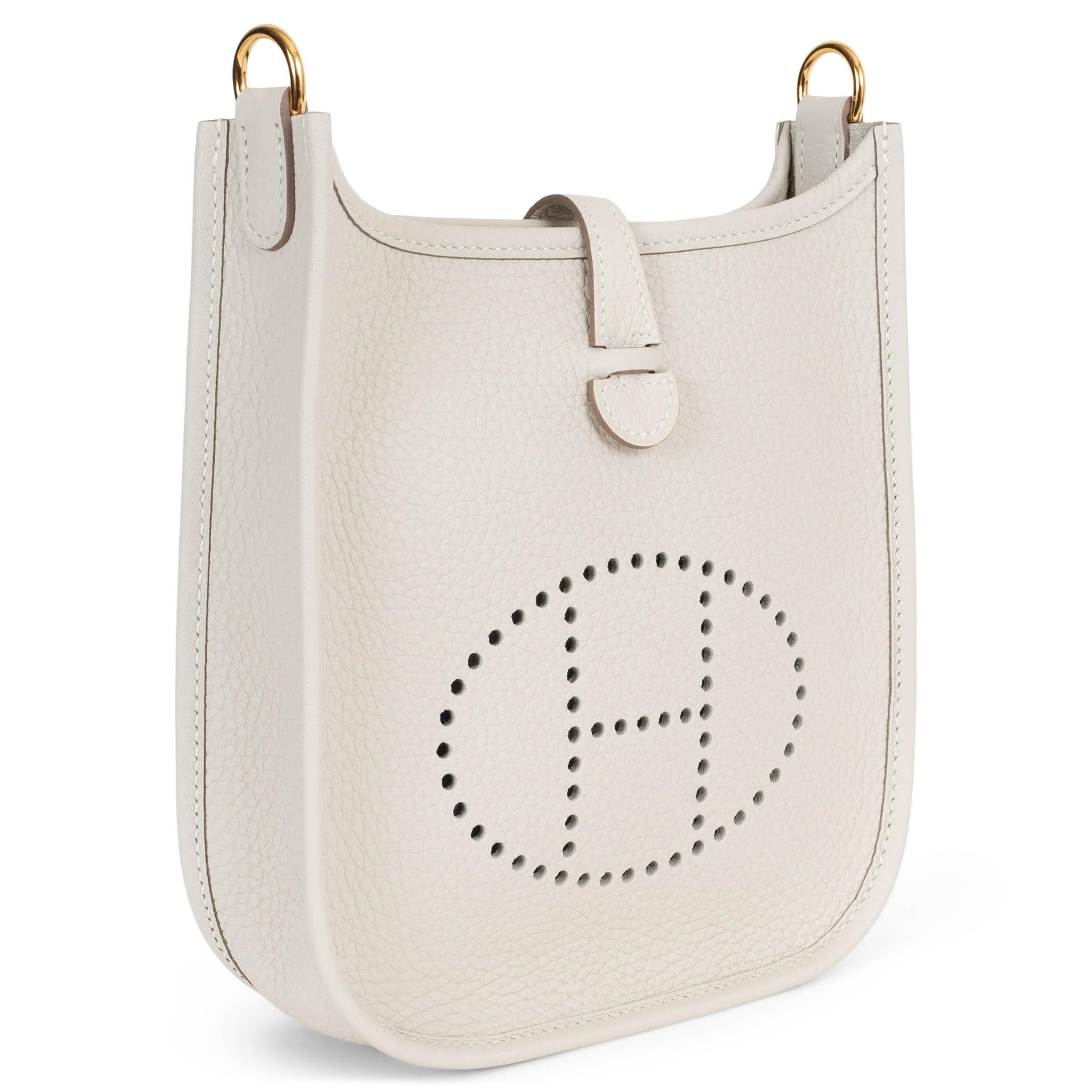 This 100% authentic Hermès Evelyne 16 TPM Crossbody Bag in Craie (chulk white) Taurillon Clemence leather is a timeless addition to any collection. Featuring the iconic perforated 