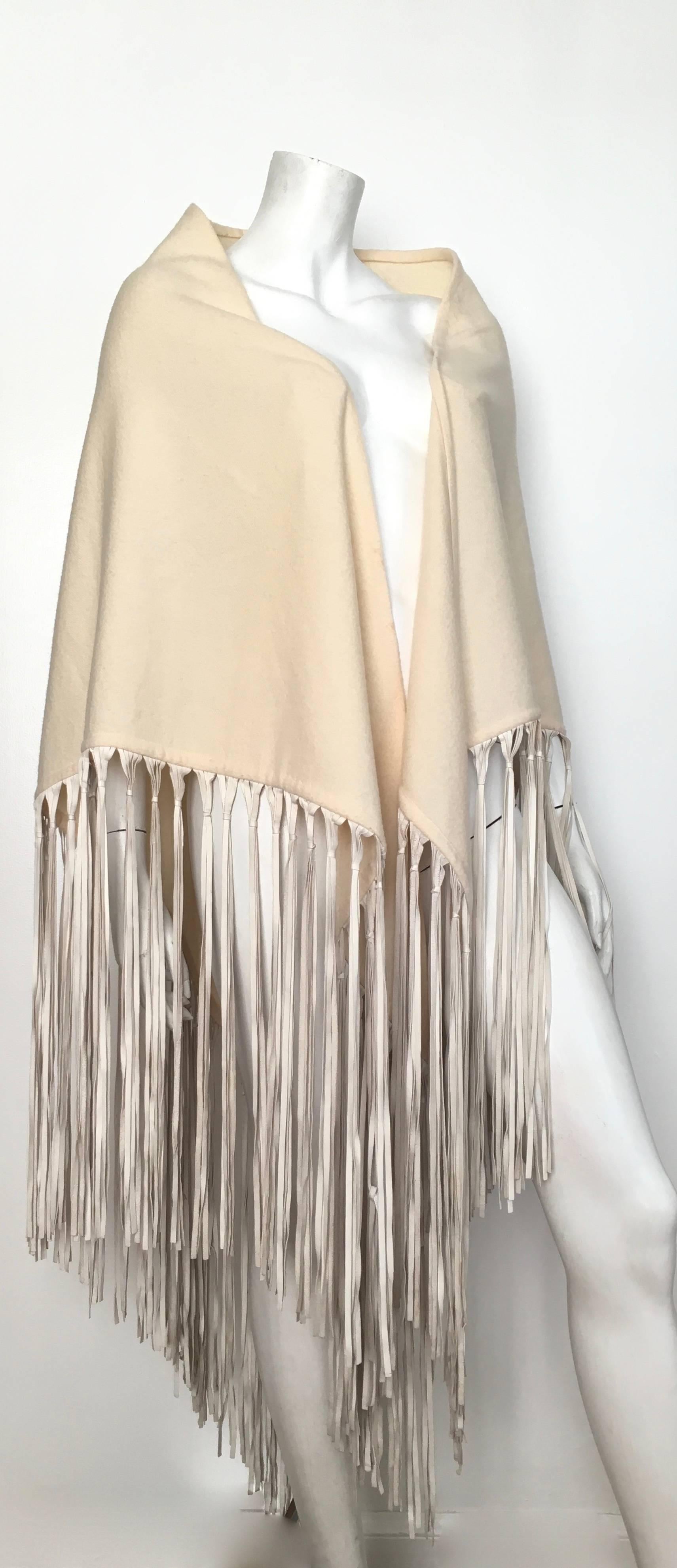 Hermes cream cashmere & wool triangular shawl with leather fringe.  This gorgeous bohemian Hermes shawl was purchased at the Hermes Paris boutique in the 1990s. There are eleven holes that have been re-woven and repaired.  There are four tiny holes