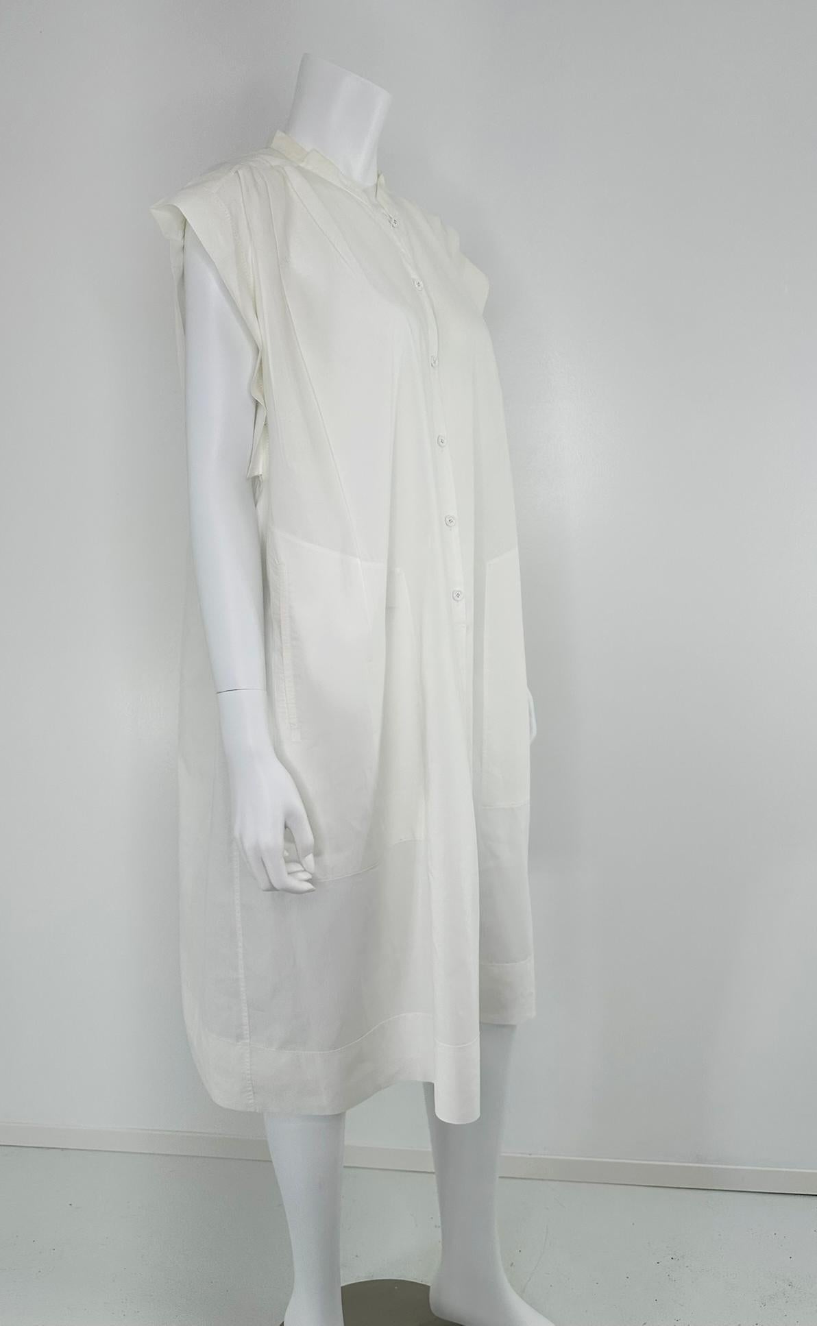 Hermes Crisp Sheer weißes Baumwollkleid mit kurzen Ärmeln, plissierter Schulter und Knopfleiste vorne. Cooles weißes Kleid aus reiner Baumwolle mit schmalem Stehkragen und Knopfleiste vorne. Die Schultern sind vorne und hinten oben in Falten gelegt,